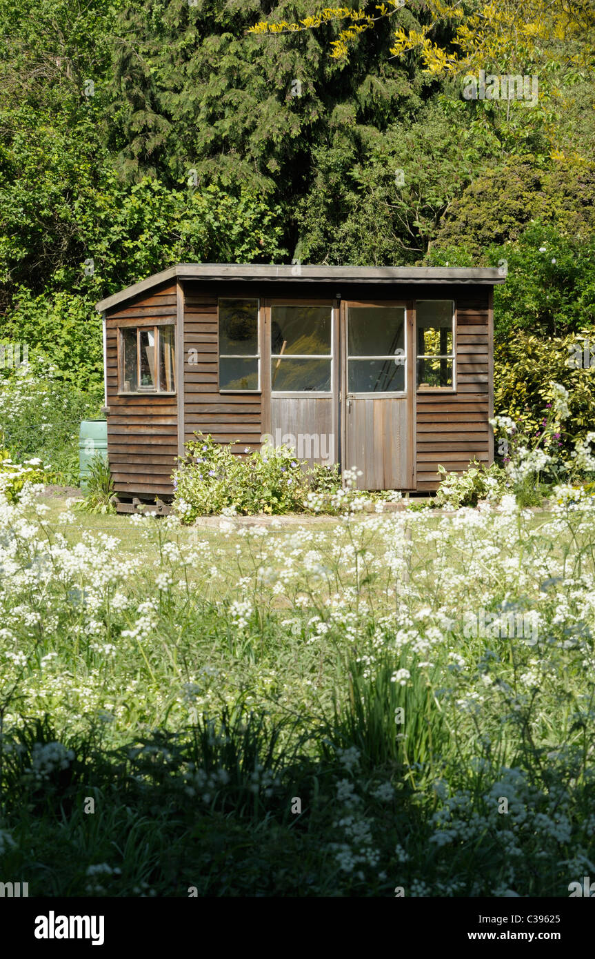 Un ancien abri de jardin en bois dans un jardin luxuriant. Banque D'Images