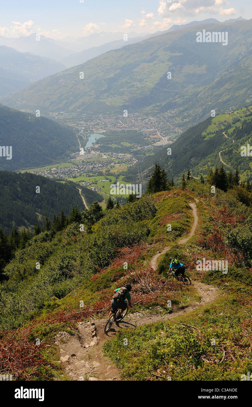 Deux cyclistes de montagne monter un sentier de la crête de la montagne vers la ville de Bourg-Saint-Maurice, dans les Alpes françaises. Banque D'Images