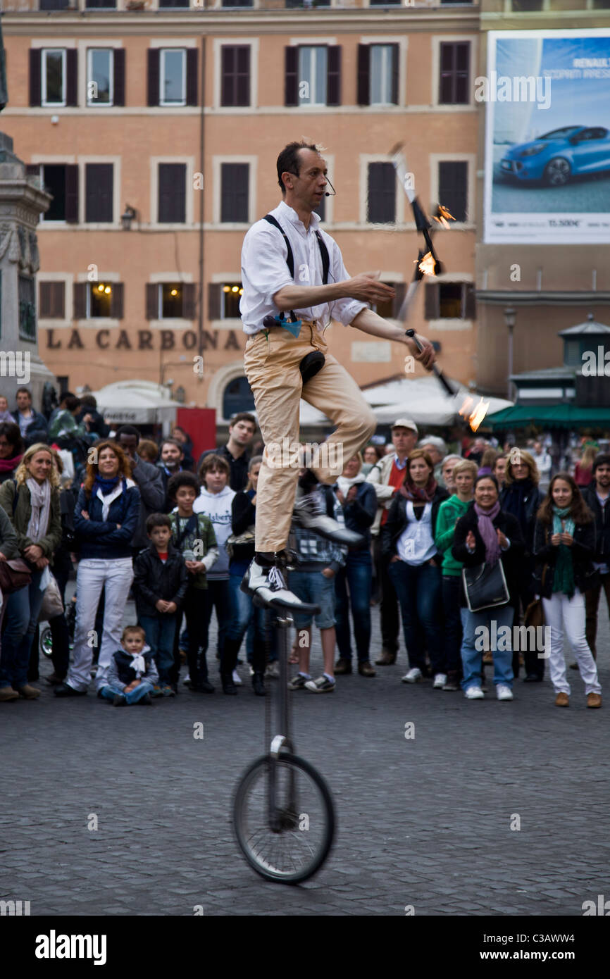 Un jongleur acrobat sur un monocycle joue avec des torches de filature à Campo de fiori, Rome, Italie Banque D'Images