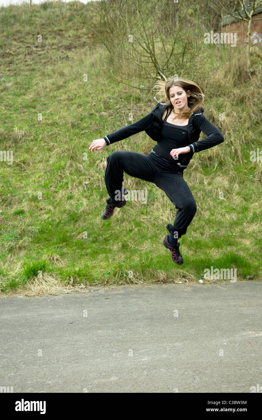 Young Caucasian woman doing tae kwon do arts martiaux coups sur le chemin près de l'Emersons Green à Bristol uk Banque D'Images