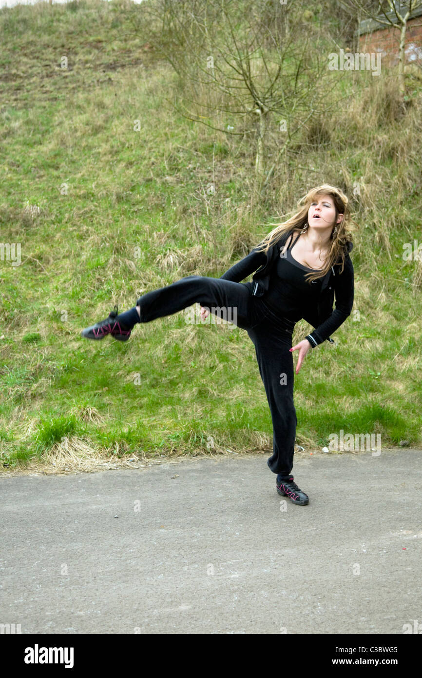 Young Caucasian woman doing tae kwon do arts martiaux coups sur le chemin près de l'Emersons Green à Bristol uk Banque D'Images