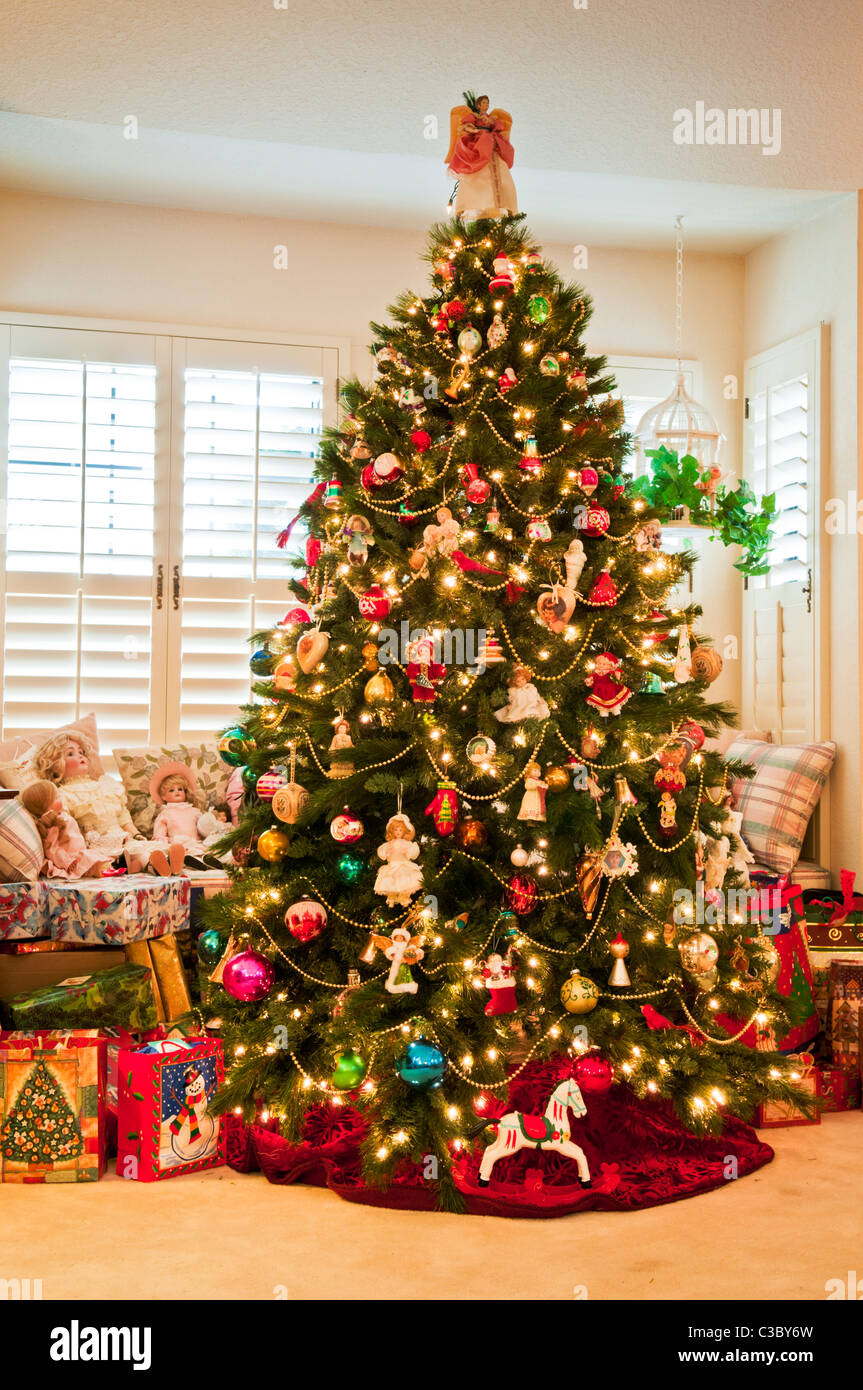 Arbre de Noël avec des décorations traditionnelles et des poupées dans la salle de séjour de la maison. Banque D'Images Arbre de Noël avec des décorations traditionnelles et des poupées dans la salle de séjour de la maison. Banque D'Images