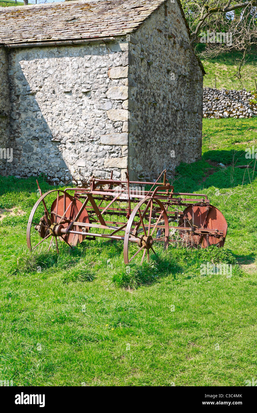 Ancien fer à repasser machines agricoles par une grange à Malham, Yorkshire du Nord, Yorkshire Dales National Park, England, UK. Banque D'Images