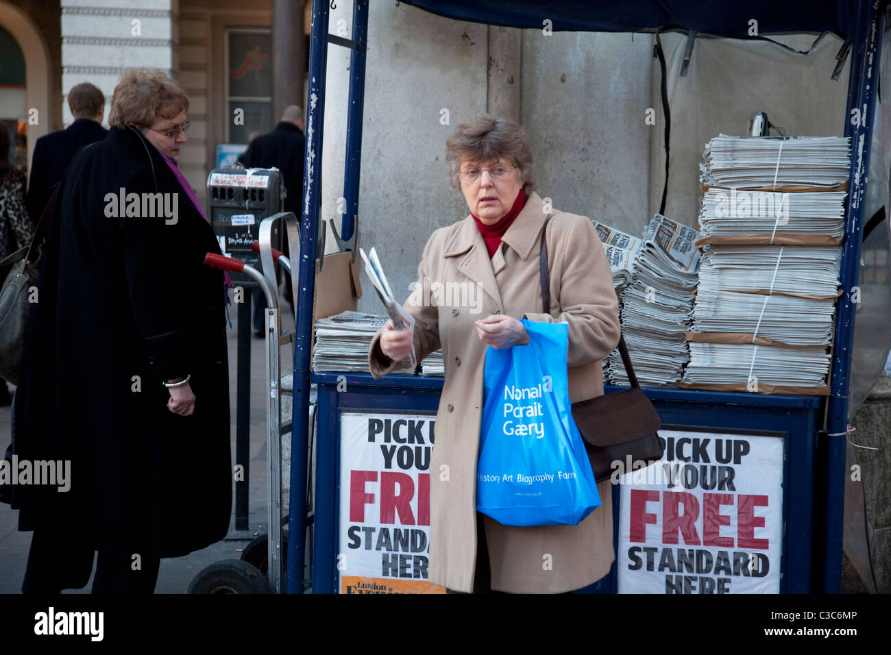Femme attrape son exemplaire du Journal de l'Evening Standard. Londres. Banque D'Images