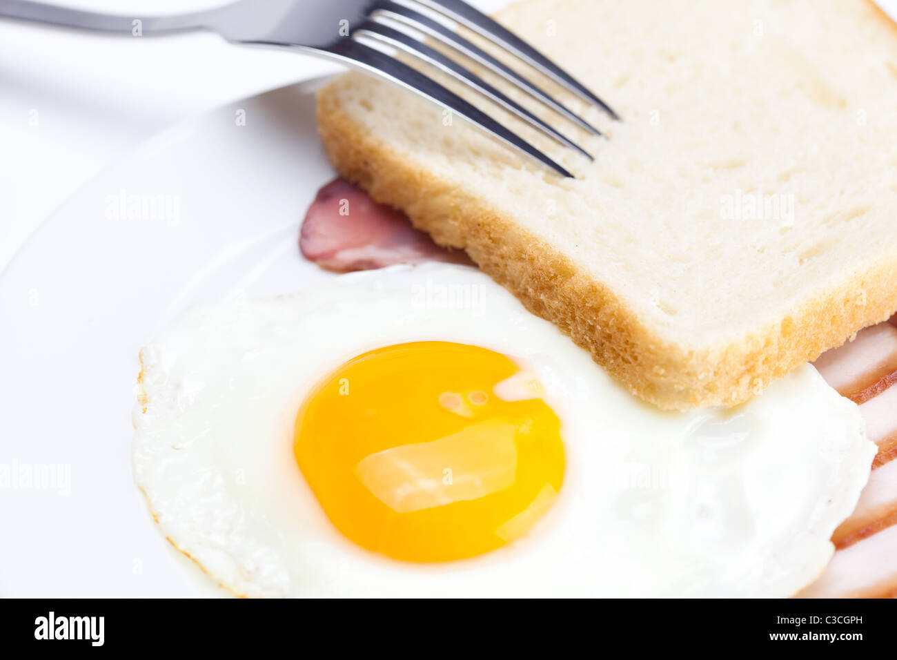 Avec les œufs au bacon dans une assiette, fourchette et pain isolated on white Banque D'Images