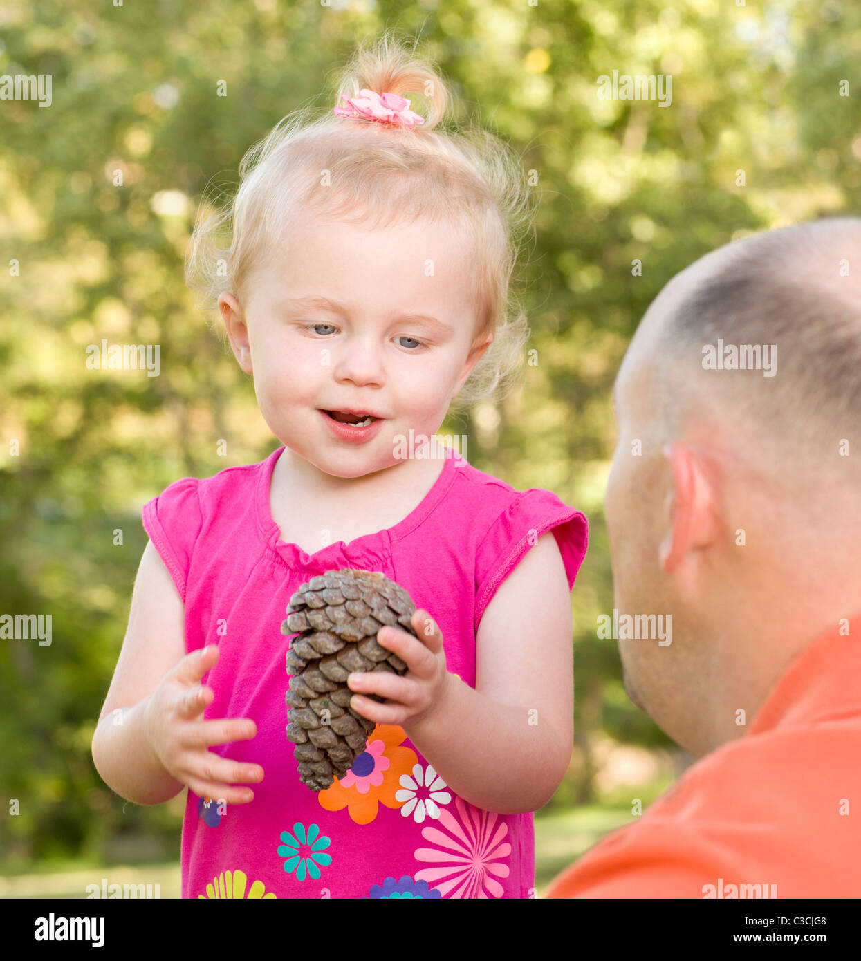 Adorable jeune Girl Holding Pine Cone parle à son père dans le parc. Banque D'Images