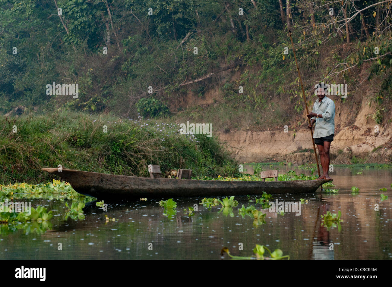 L'homme Local polonais une pirogue sur un fleuve dans le parc national de Chitwan dans la région du Teraï subtropical du Népal Banque D'Images