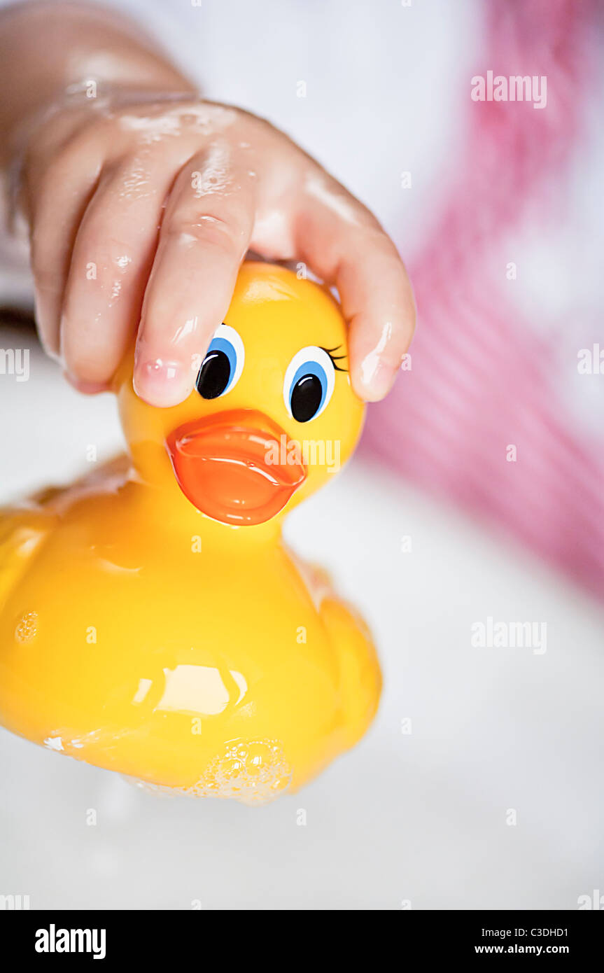 Le bain plaisir ! Tout-petit main tenant un canard en caoutchouc jaune  au-dessus d'une baignoire pleine d'eau et de bulles Photo Stock - Alamy