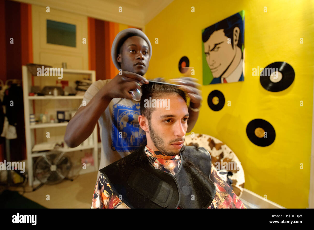 Young male hairdresser cutting cheveux du client dans le hip coiffure Banque D'Images