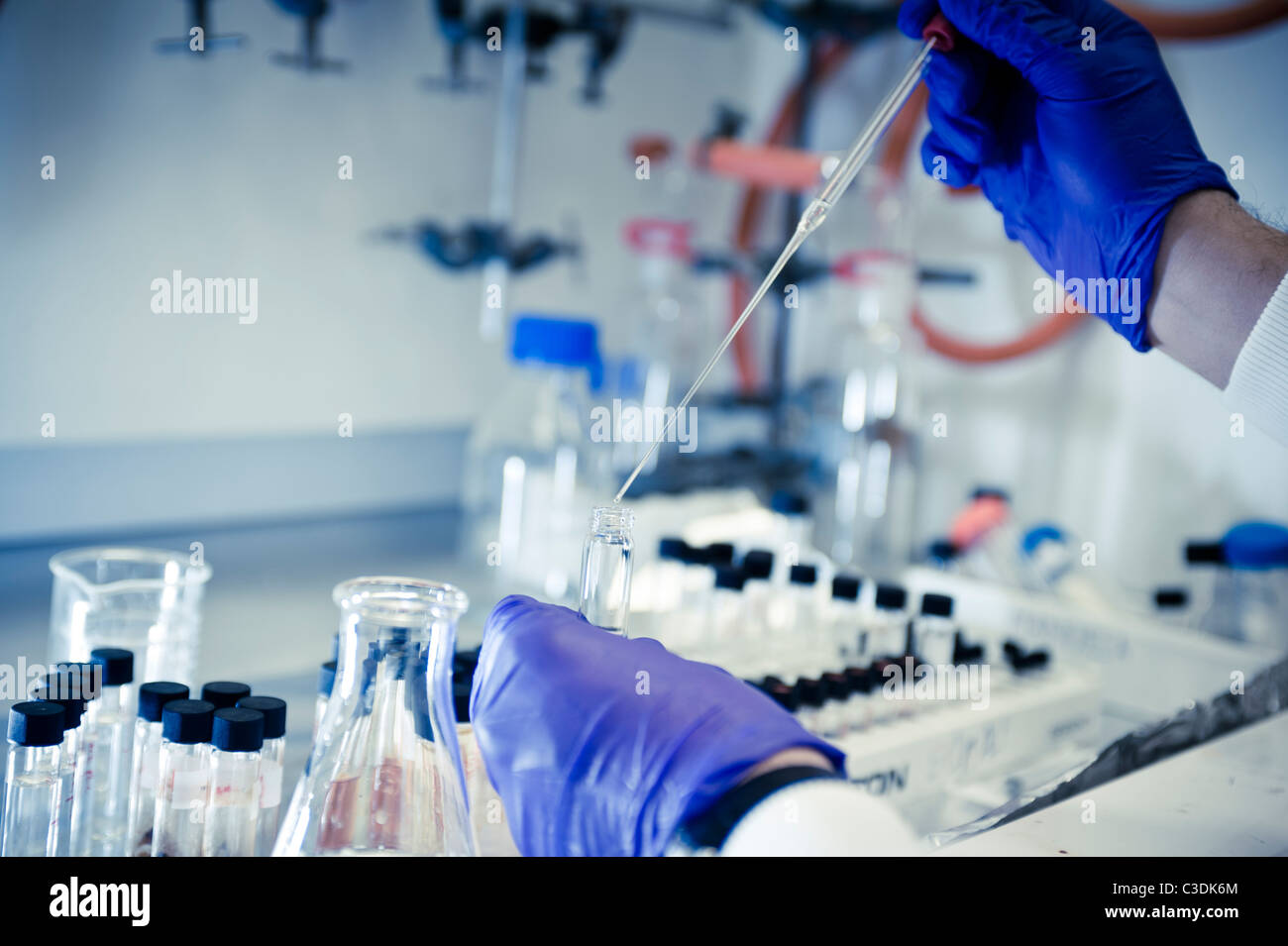 Close up of male scientist wearing sarrau blanc lunettes et gants violet travaillant à hotte à la pipette et flacons Banque D'Images