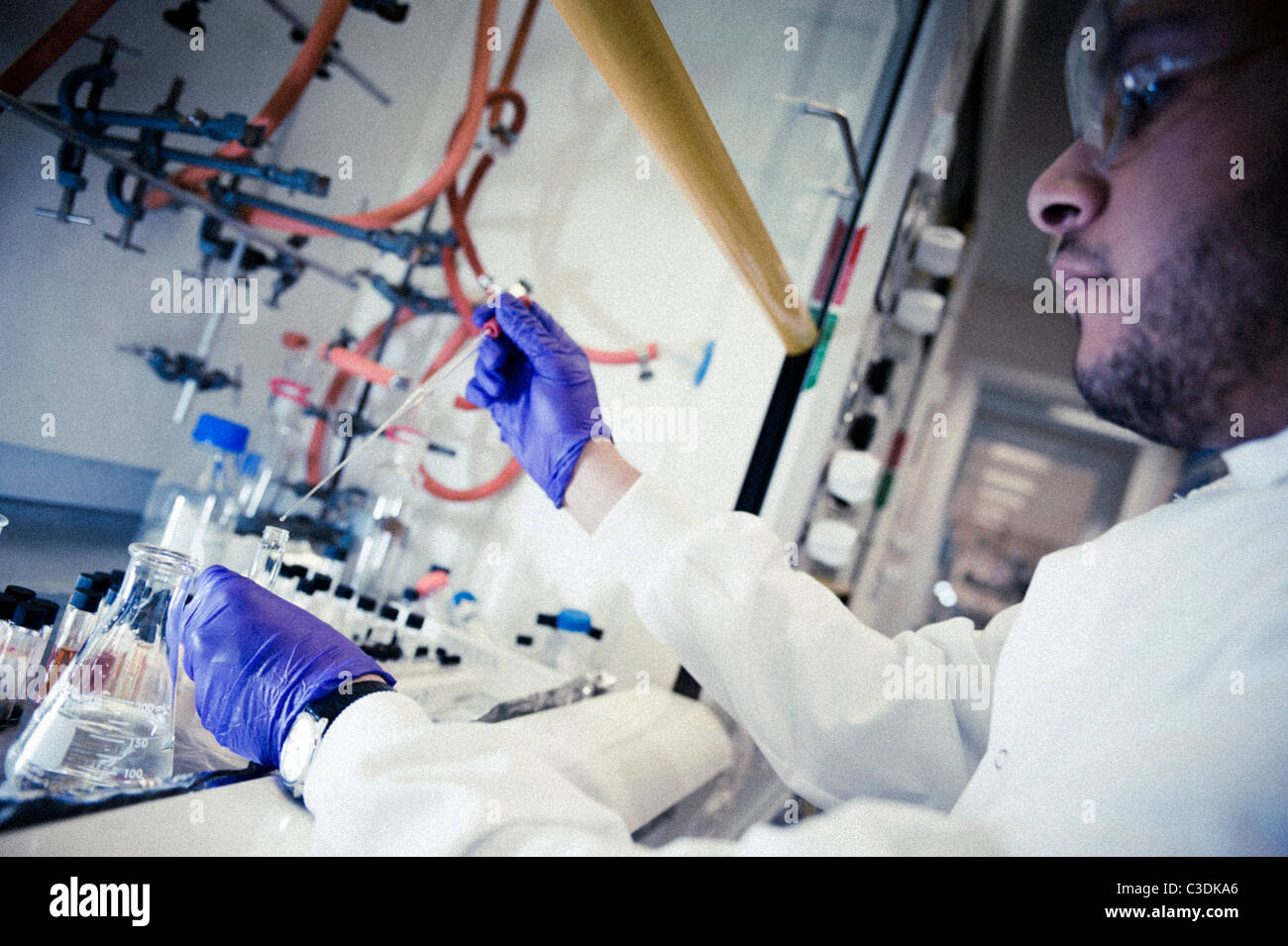 Close up of male scientist wearing sarrau blanc lunettes et gants violet travaillant à hotte à la pipette et flacons Banque D'Images
