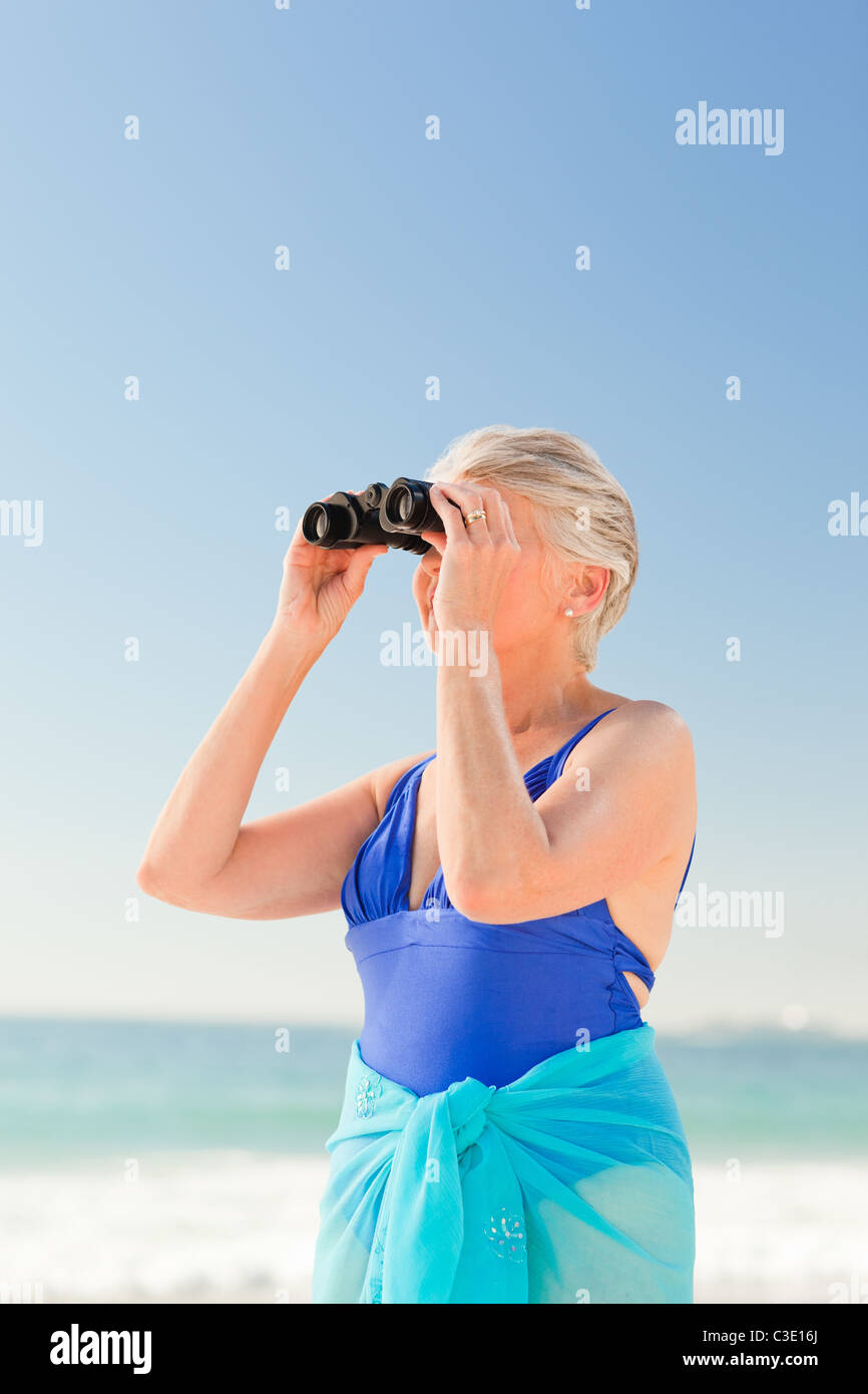 Senior woman l'observation des oiseaux à la plage Banque D'Images