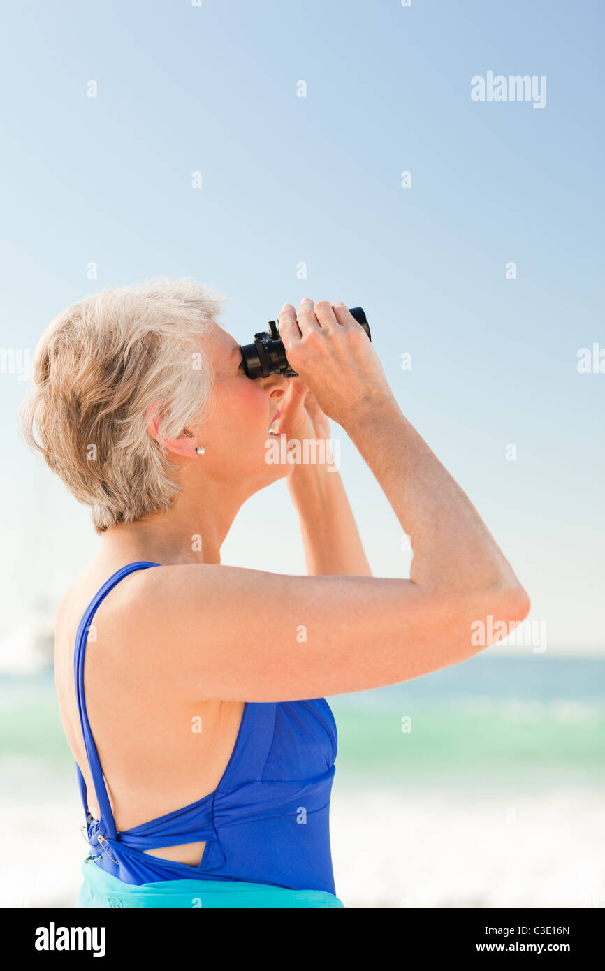 Senior woman l'observation des oiseaux à la plage Banque D'Images