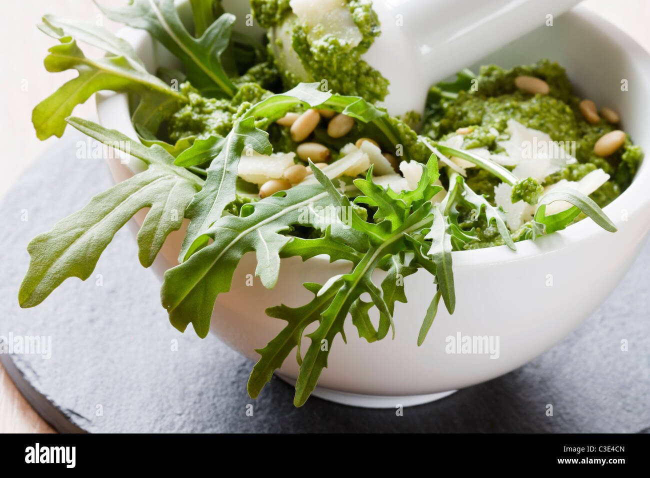 La préparation de pesto de roquette à l'aide d'un mortier. Banque D'Images