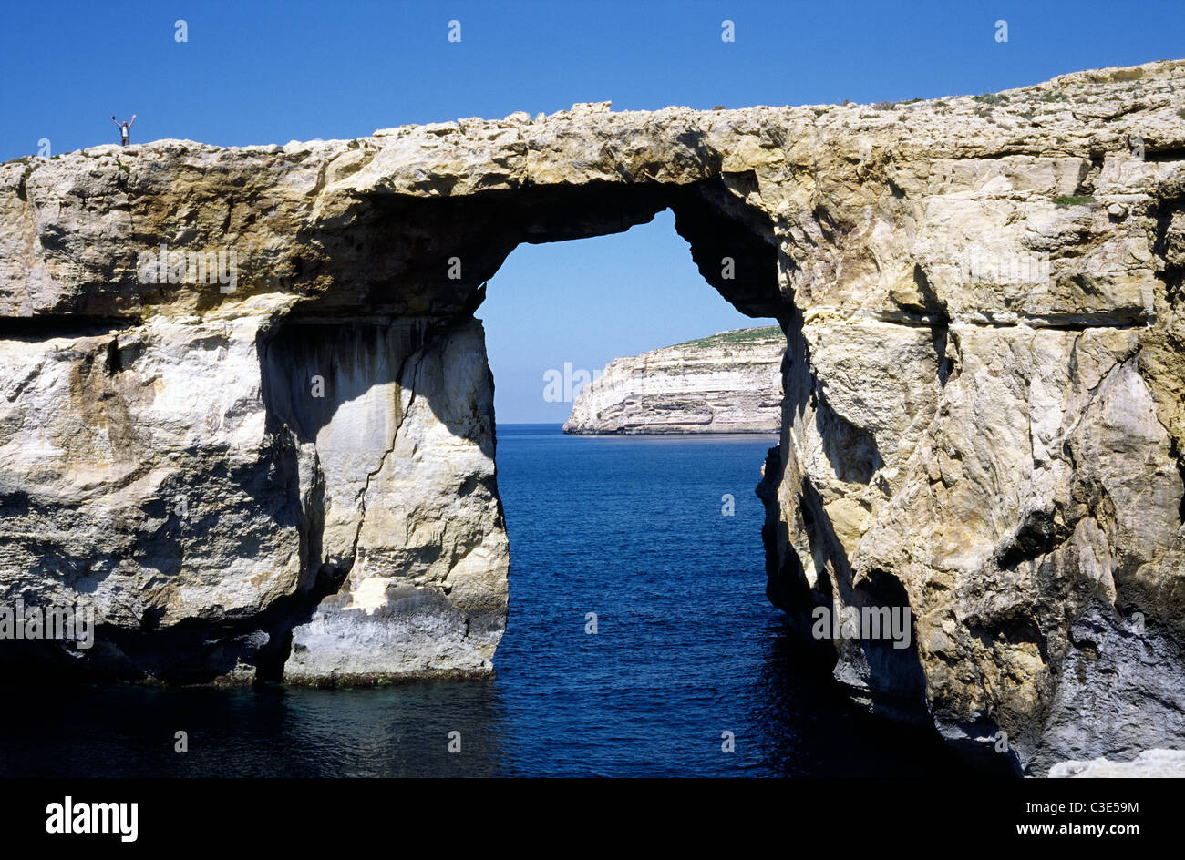 Tourist debout sur la fenêtre d'Azur à Dwejra Point sur l'île maltaise de Gozo. Banque D'Images