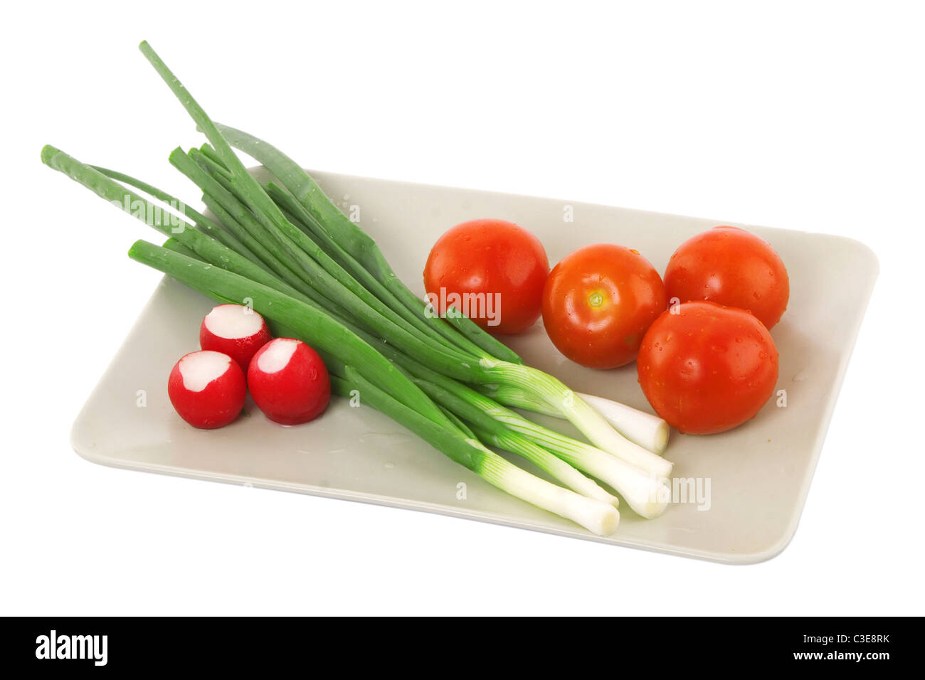 Plaque blanche avec la tomate, le radis et l'oignon vert, la nourriture végétarienne Banque D'Images