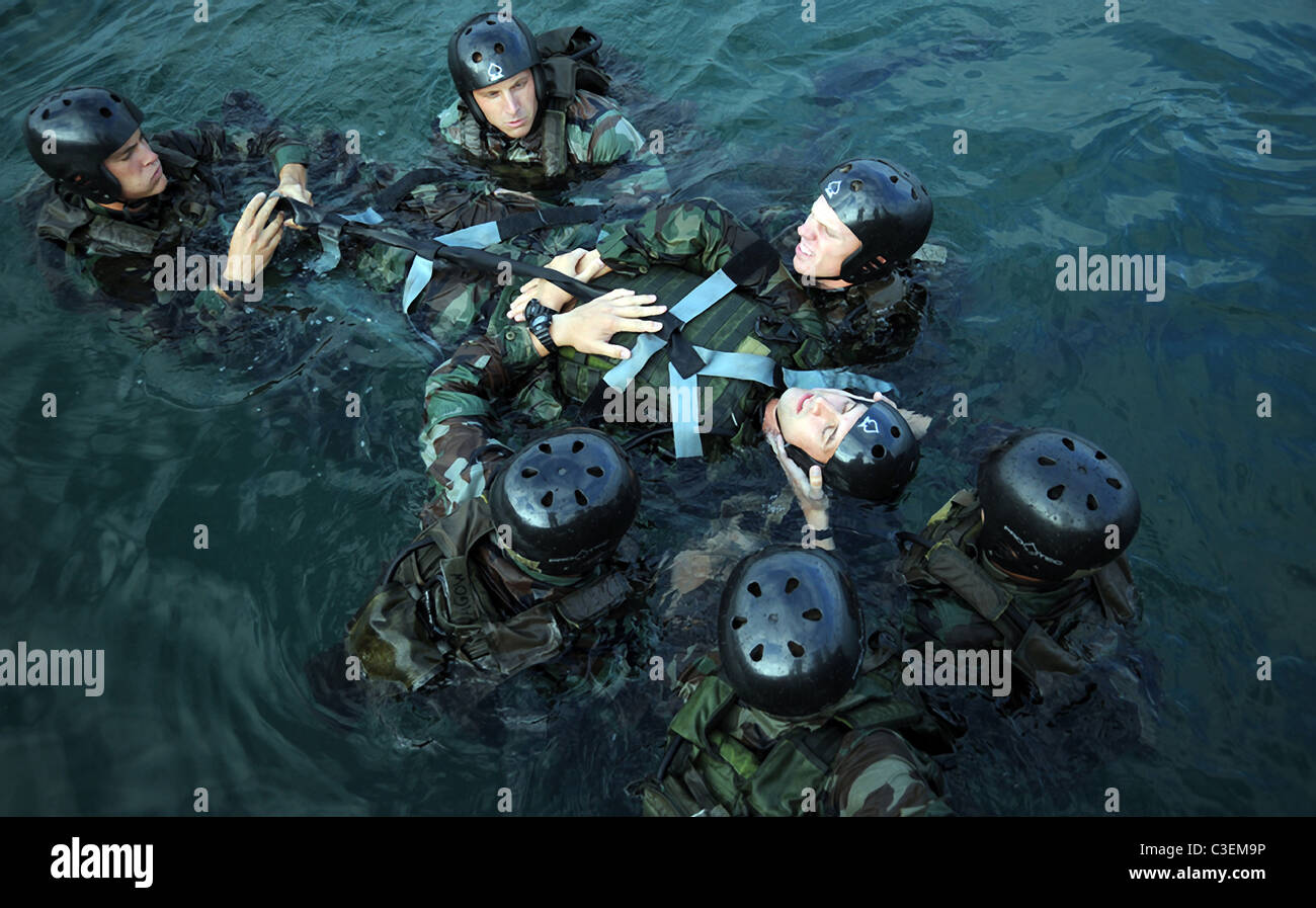 Navy SEAL stagiaires sécuriser une victime simulée d'une planche dorsale au cours d'un scénario de formation médicale à la Naval Amphibious Base Banque D'Images