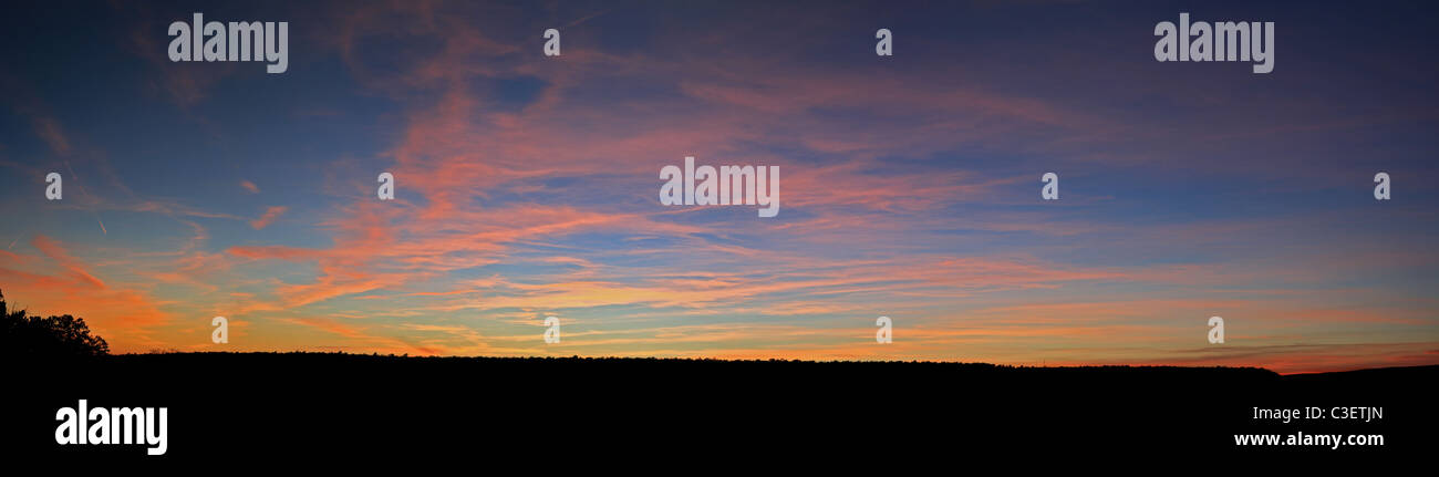Panorama d'un coucher du soleil avec ciel bleu et nuages orange et jaune Banque D'Images