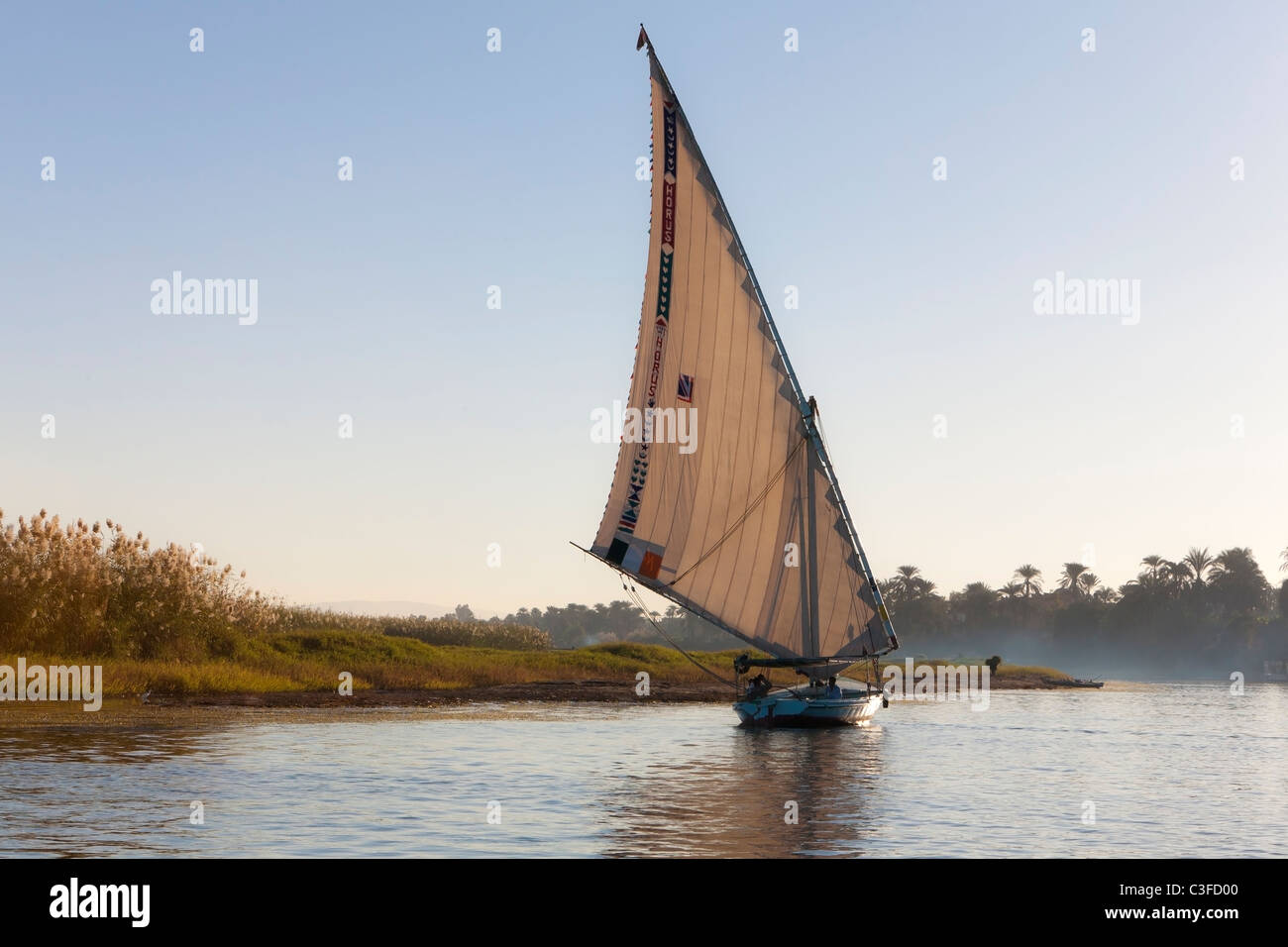 Felouque voile à proximité d'une île sur le Nil au coucher du soleil, Luxor, Egypte, Afrique du Nord Banque D'Images