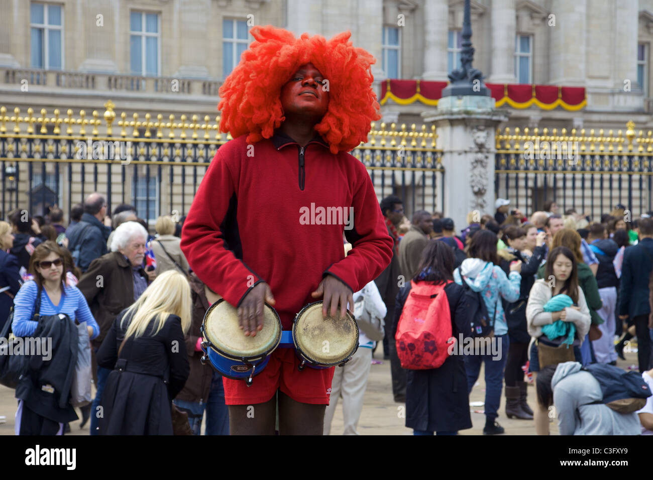 Un homme à l'extérieur de Buckingham Palace pour le mariage royal de prince William et Kate Middleton jouant les bongos, Londres Banque D'Images