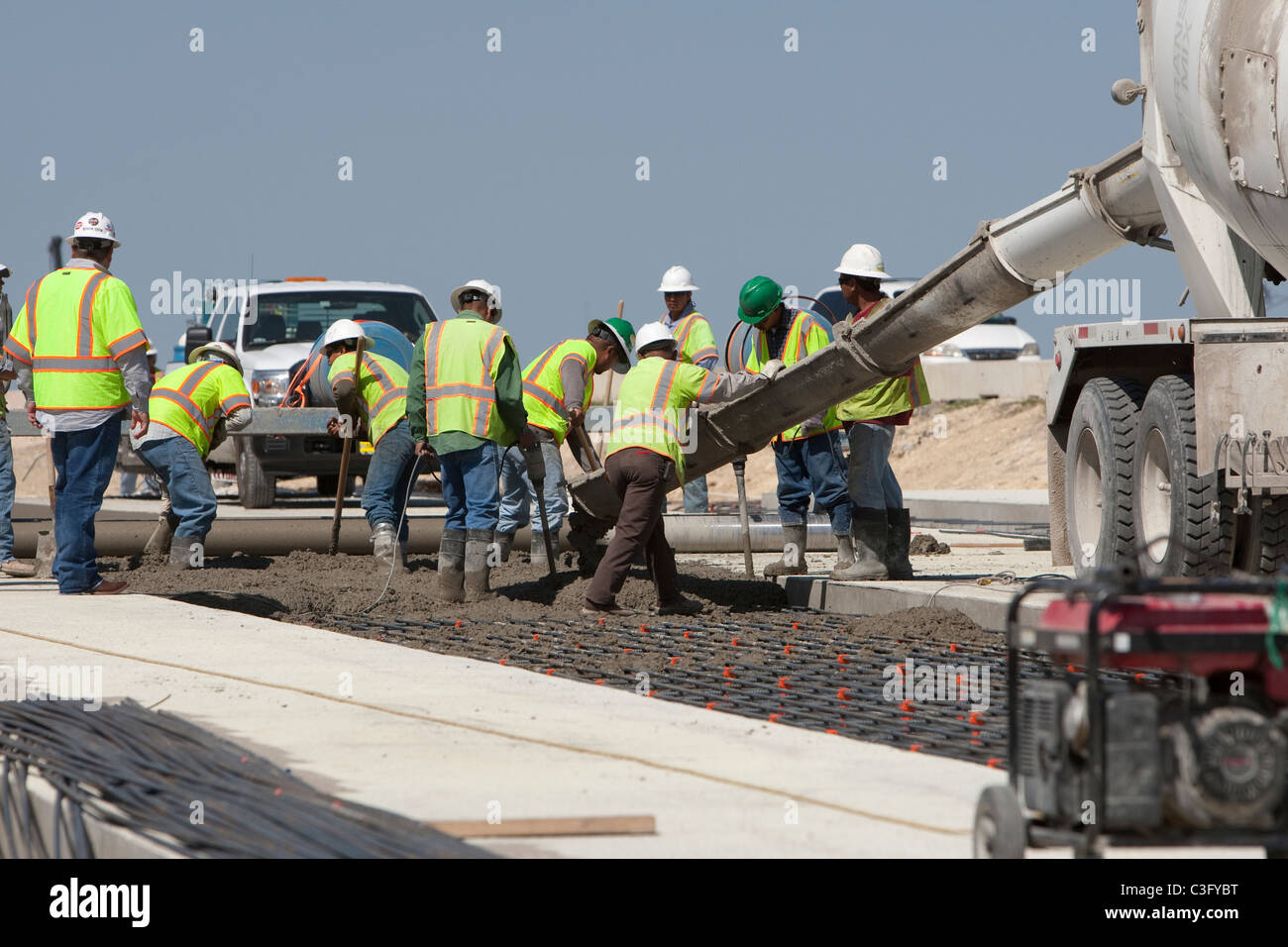 Équipe de travailleurs de la construction de la route des hommes pour le béton frais sur l'age de la grille pour s'étirer de nouveau la construction routière dans le Texas Banque D'Images