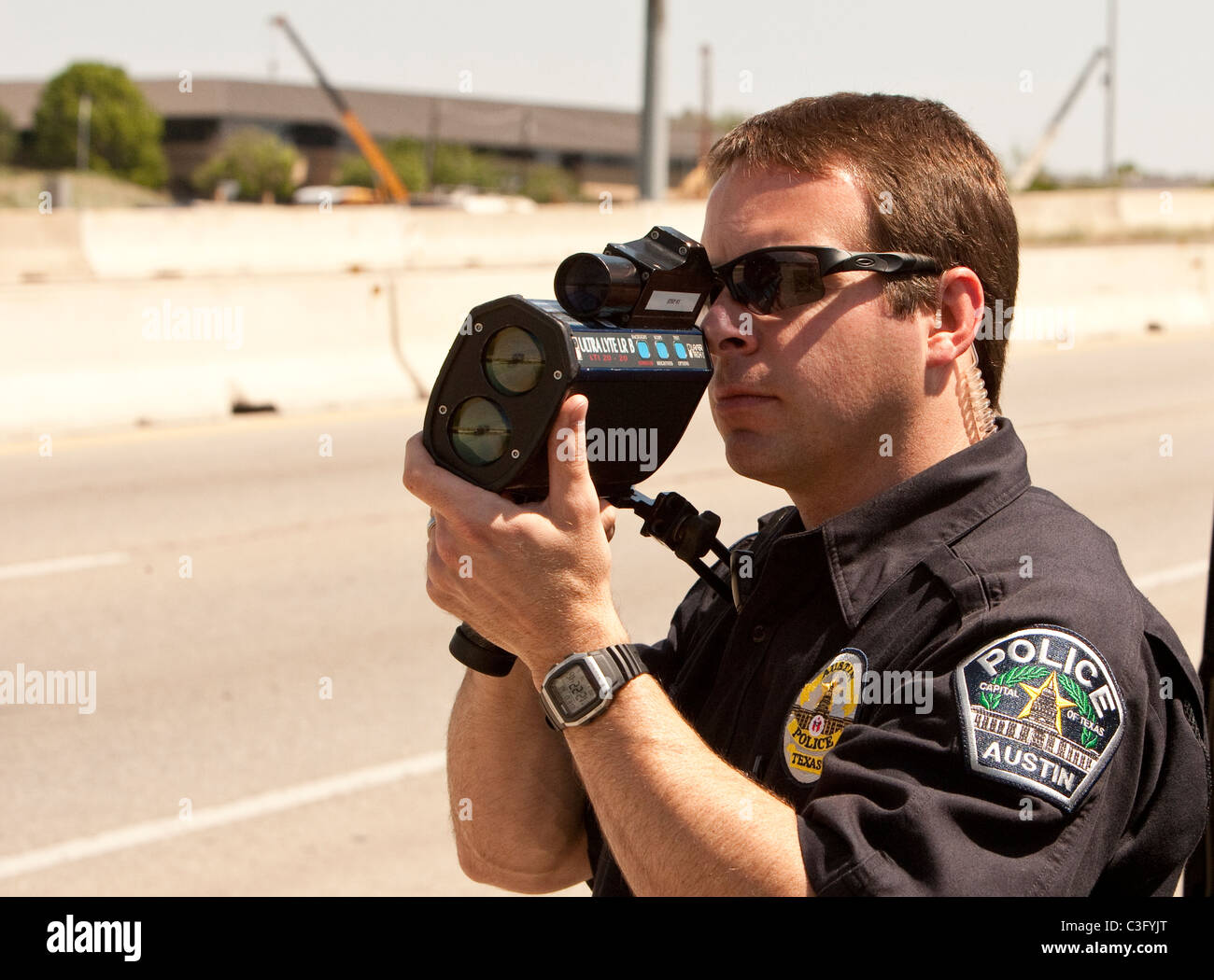 Agent de police de sexe masculin utilise des armes à feu de vitesse radar pour attraper les conducteurs excès de vitesse sur l'autoroute à Austin, Texas USA Banque D'Images