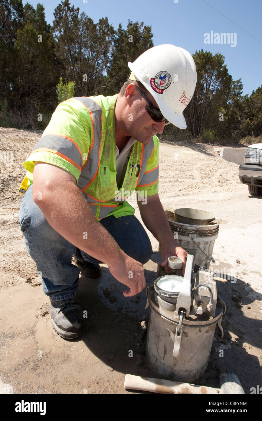 Travailleur homme utilise gage pour mesurer la quantité d'air dans le béton le long de la construction de l'autoroute à Austin, Texas Banque D'Images
