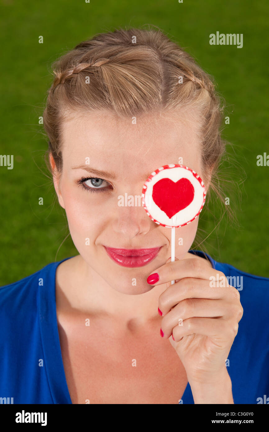 Beau Portrait de jeune fille blonde avec une sucette coeur dans sa main Banque D'Images