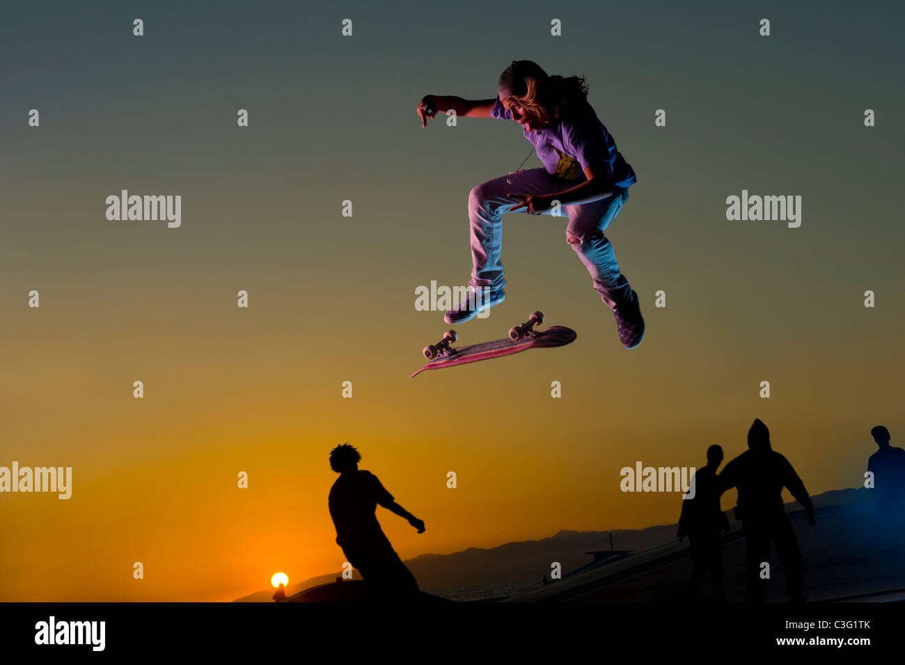 Skateboarder caucasienne faisant stunt en plein vol au coucher du soleil Banque D'Images