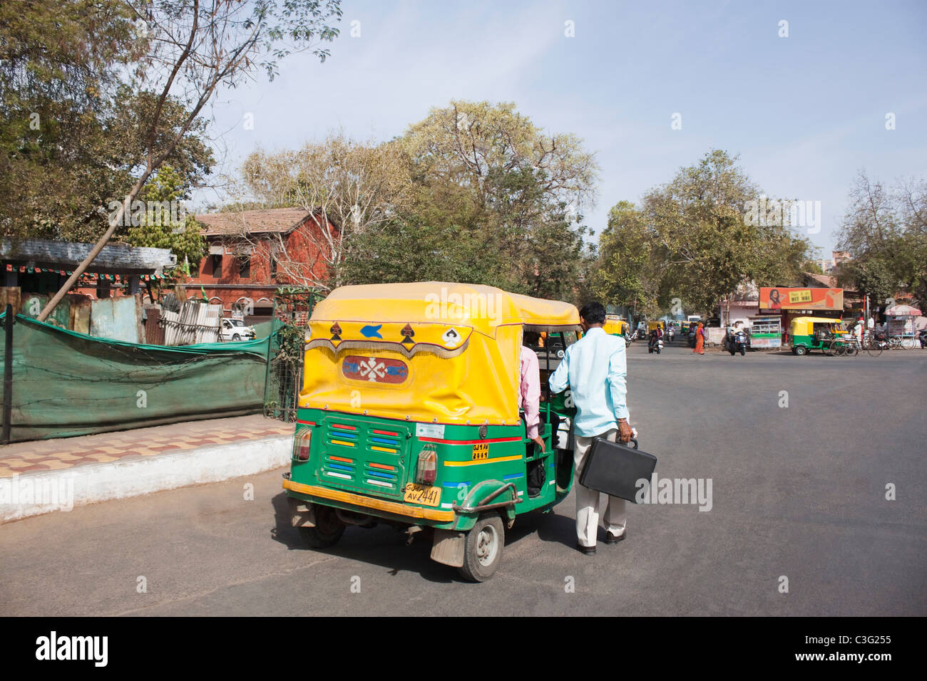 Homme debout près d'un auto rickshaw, Ahmedabad, Gujarat, Inde Banque D'Images