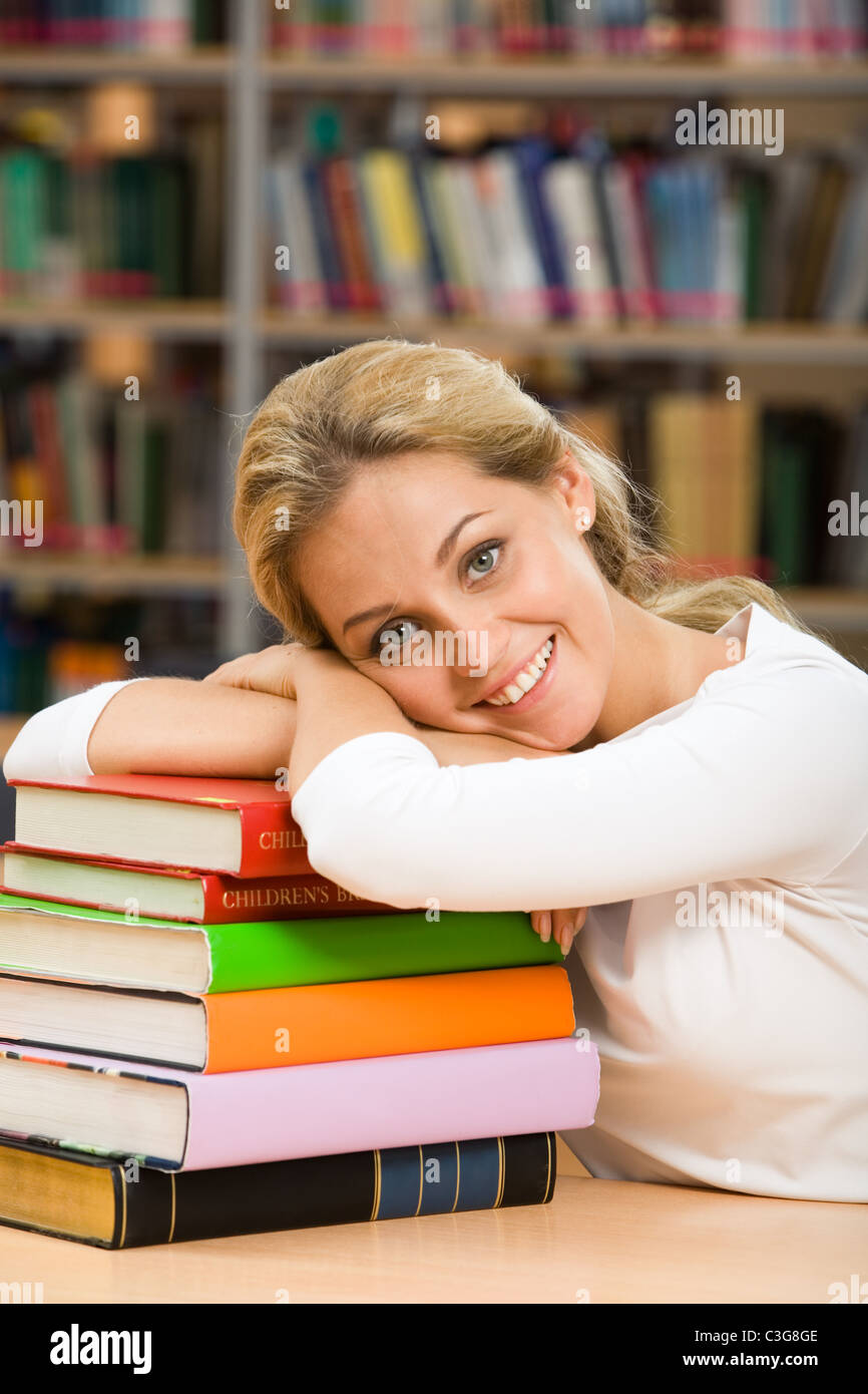 Photo de smiling teacher mettant sa tête sur pile de livres et looking at camera Banque D'Images