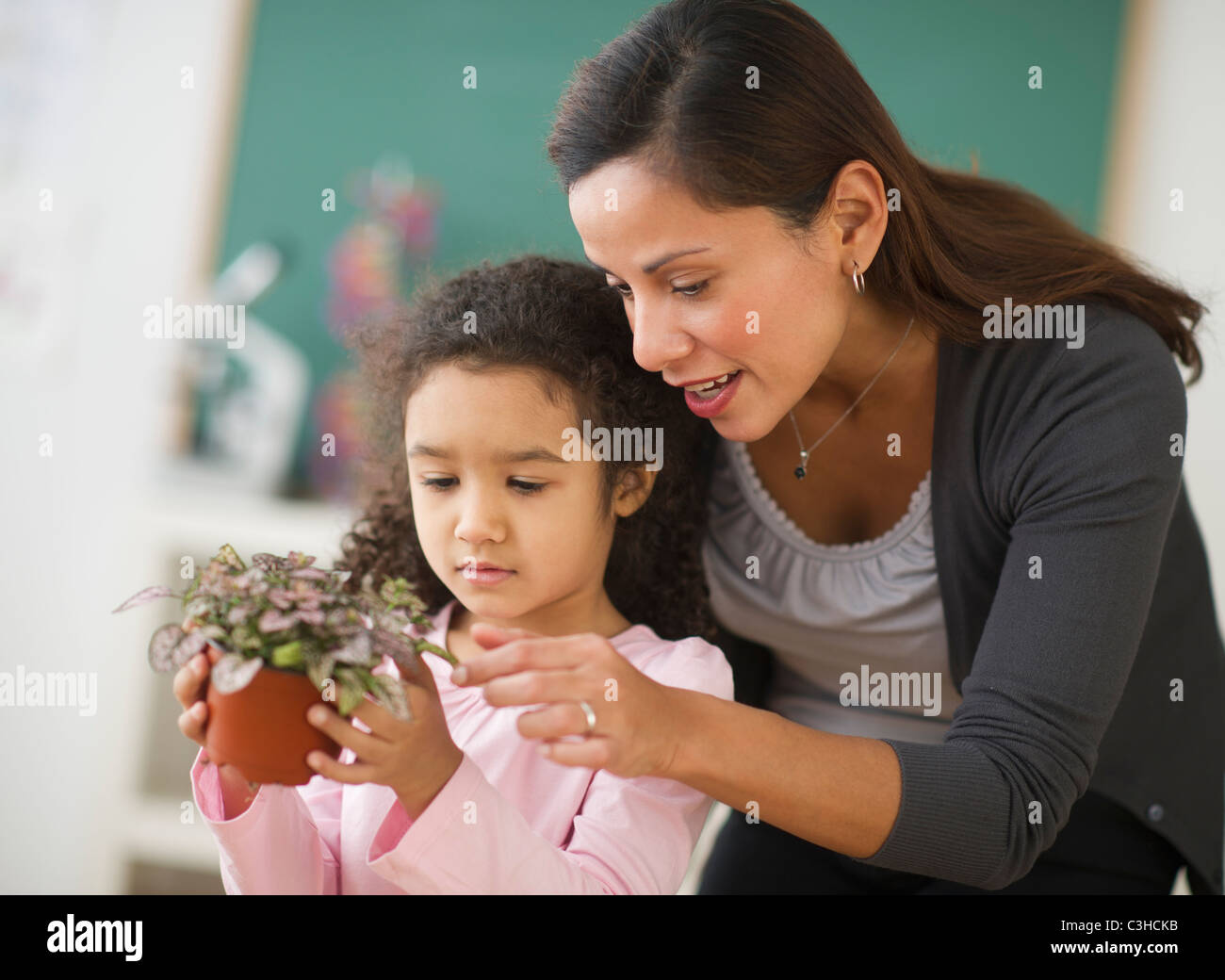 Girl (6-7) holding potted plant avec enseignante Banque D'Images