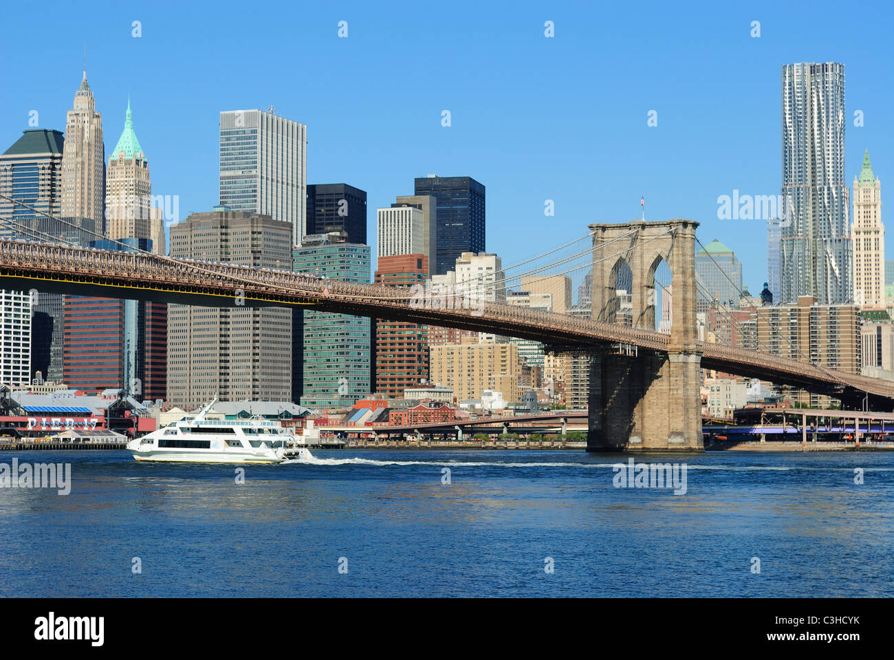 Un bateau de croisière sur l'East River titre sous le pont de Brooklyn à New York. Banque D'Images