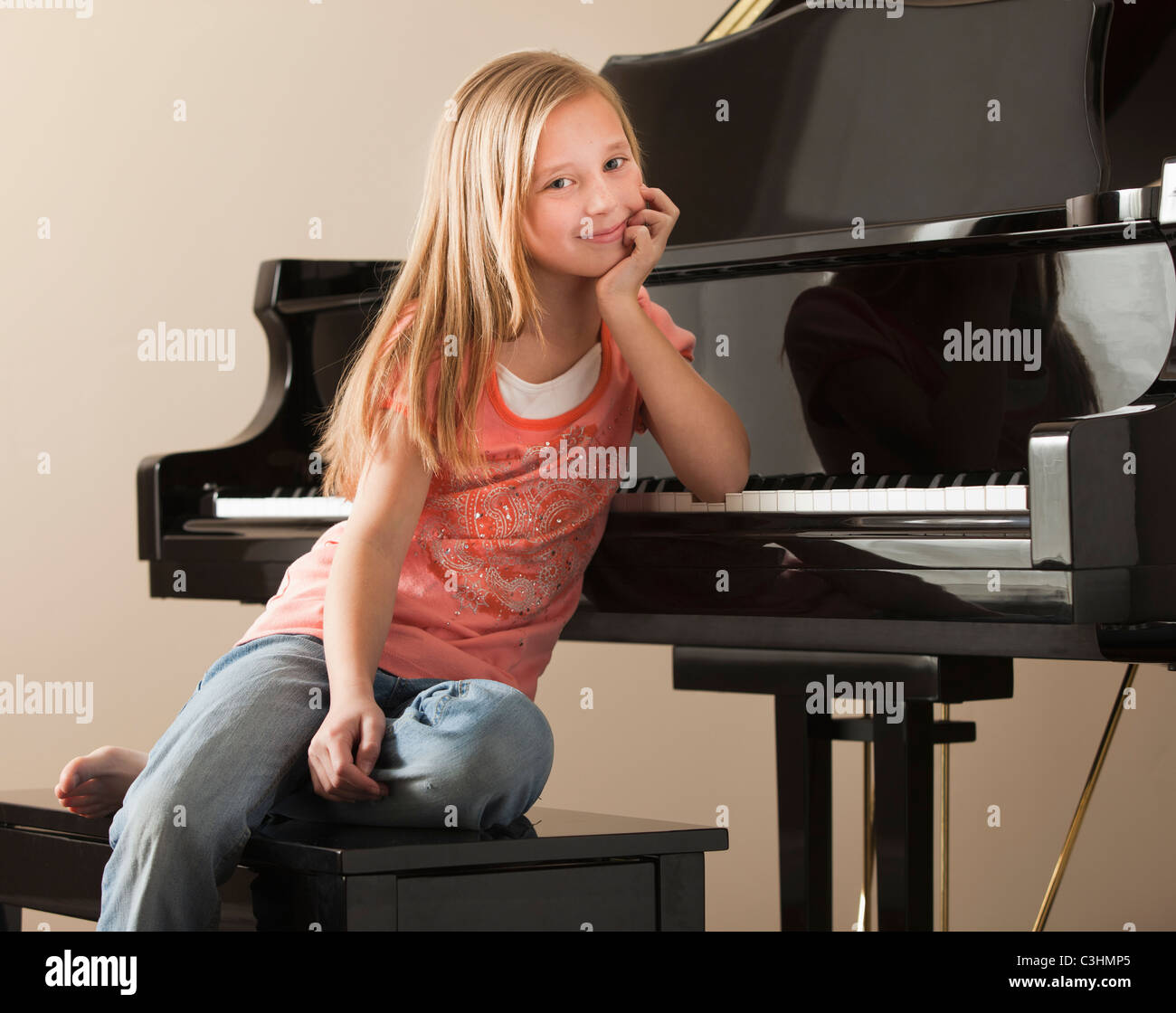 Portrait of Girl (8-9) sitting par piano Banque D'Images