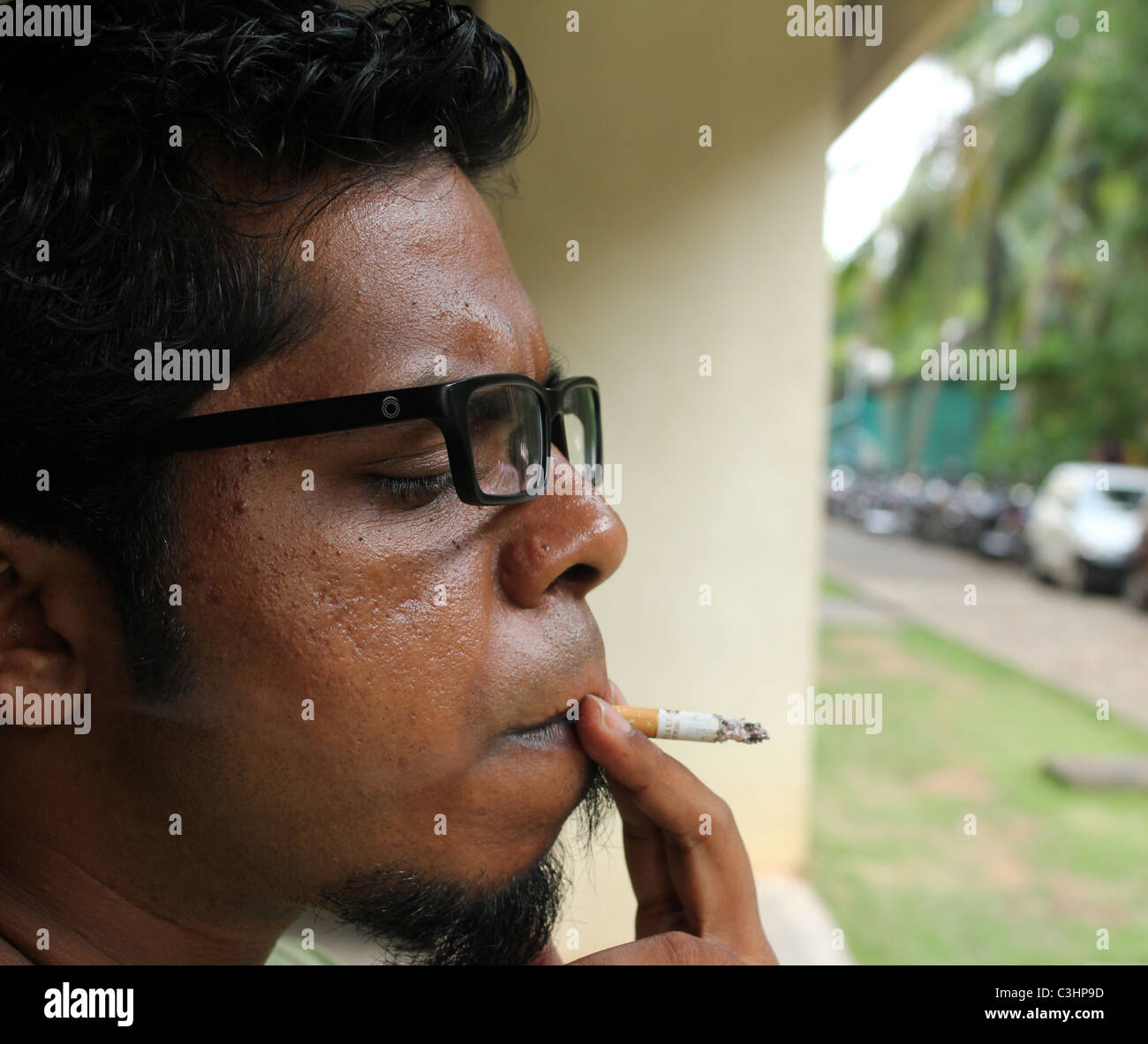 Profil de côté d'une jeune sud-asiatique spectacle cigarette tabac lunettes lunettes lunettes specs Banque D'Images