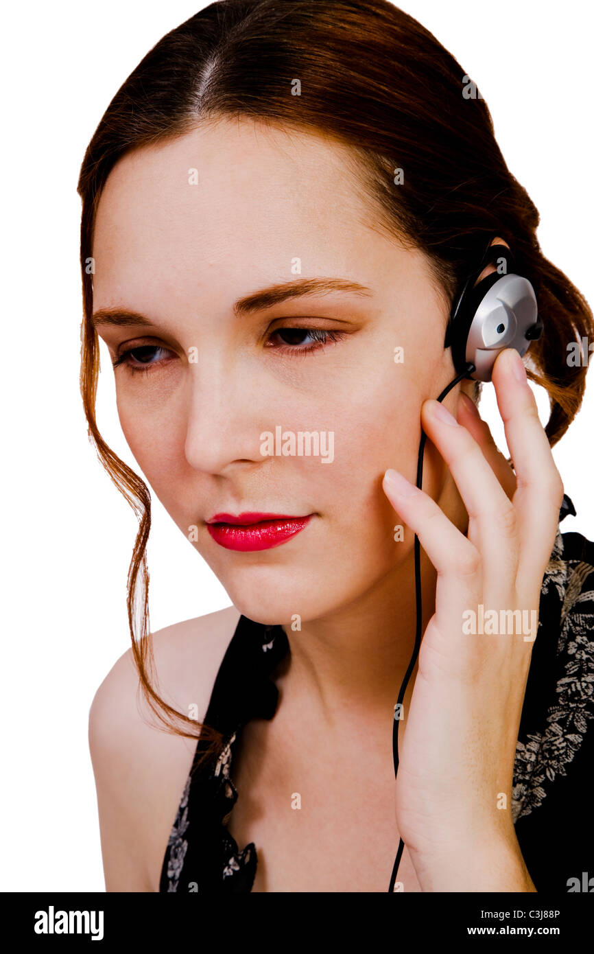 Close-up of a woman listening to music on headphones isolated over white un Banque D'Images