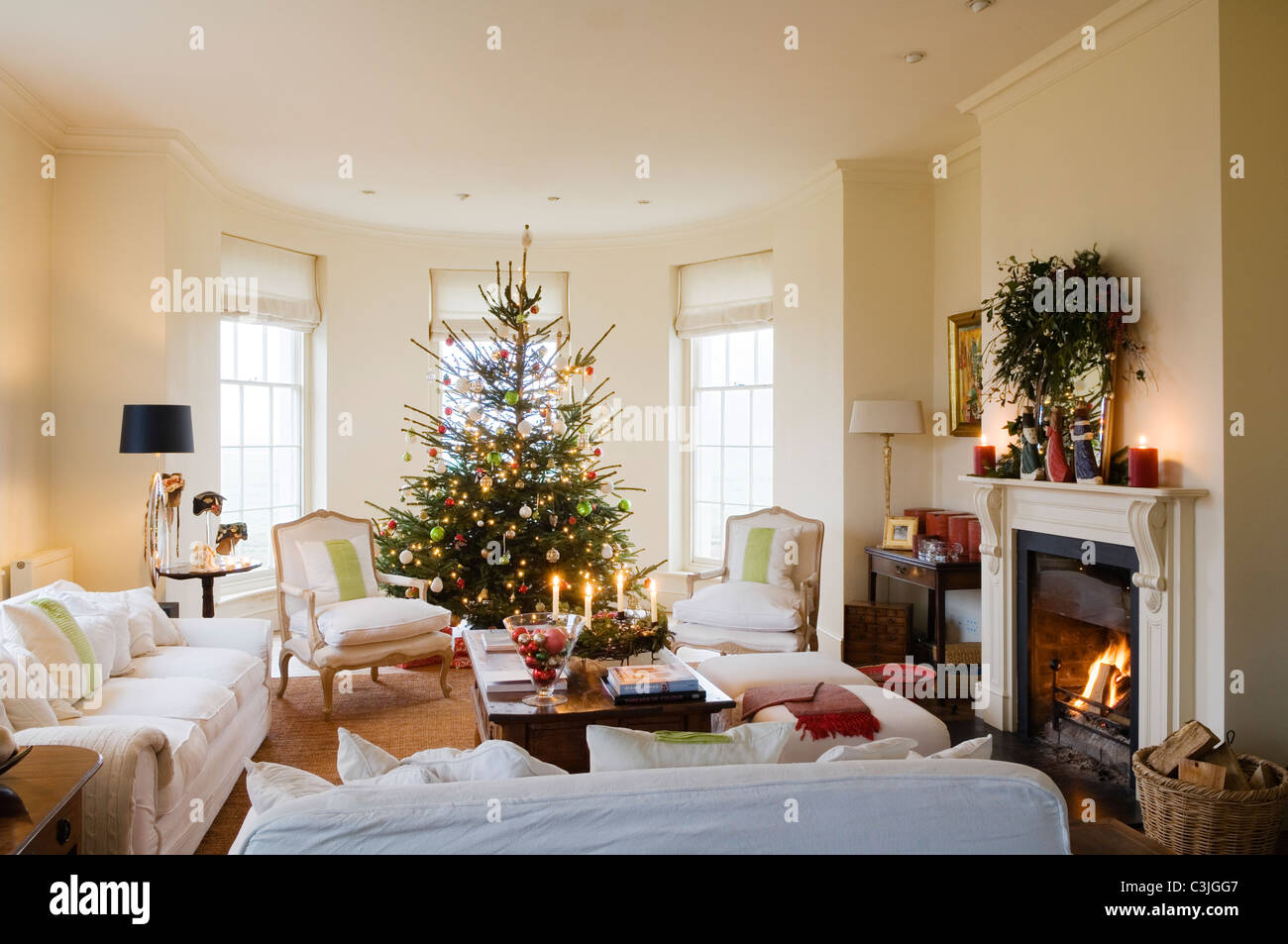 Arbre de Noël décoré avec des babioles dans regency salon avec fauteuils et cheminée Banque D'Images