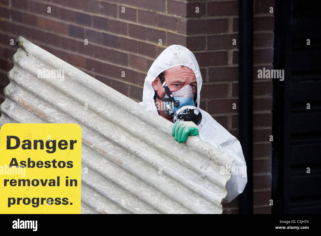 Un spécialiste de l'enlèvement de l'amiante société Suppression d'amiante sur un toit en appentis d'une maison à Ambleside, Cumbria, Royaume-Uni. Banque D'Images