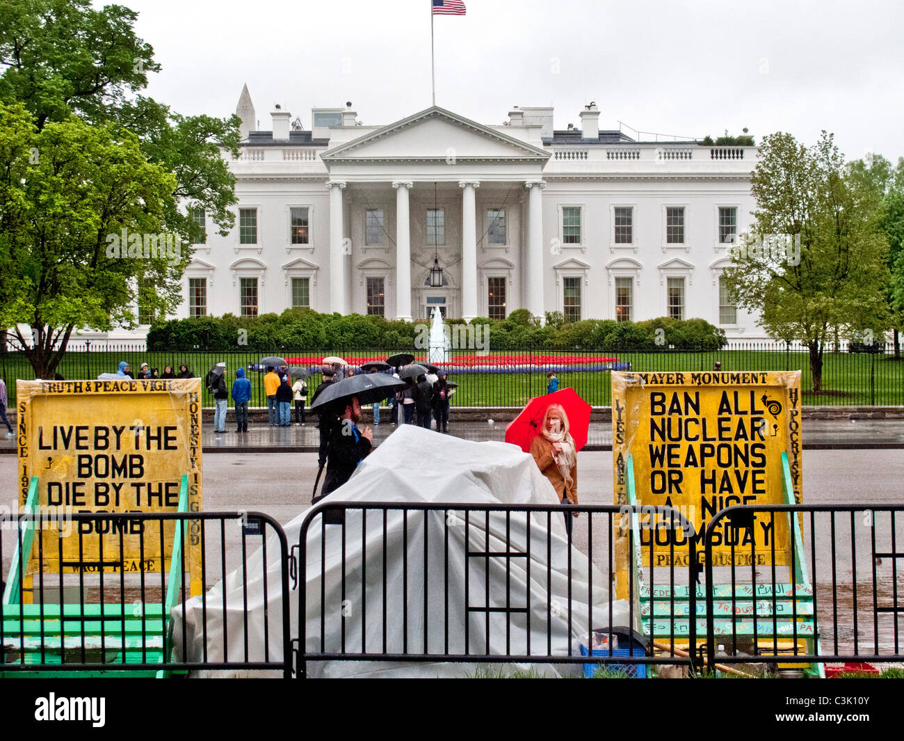 Le port d'imperméables et de parapluies, transportant les touristes se rassemblent devant la Maison Blanche à Washington, D.C. Note de protestation anti-nucléaire. Banque D'Images