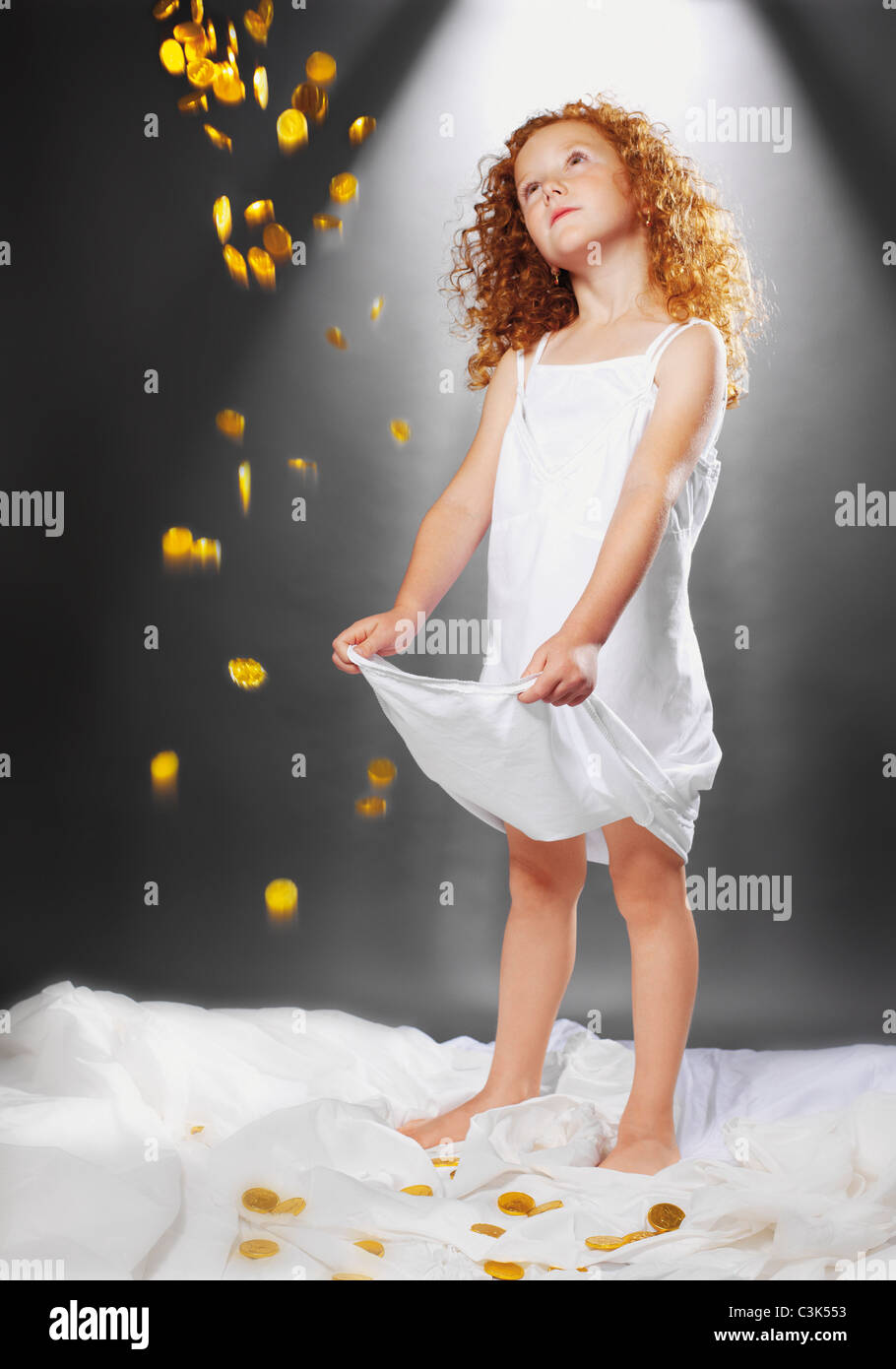Girl catching douche de pièces d'or dans l'habillement Banque D'Images