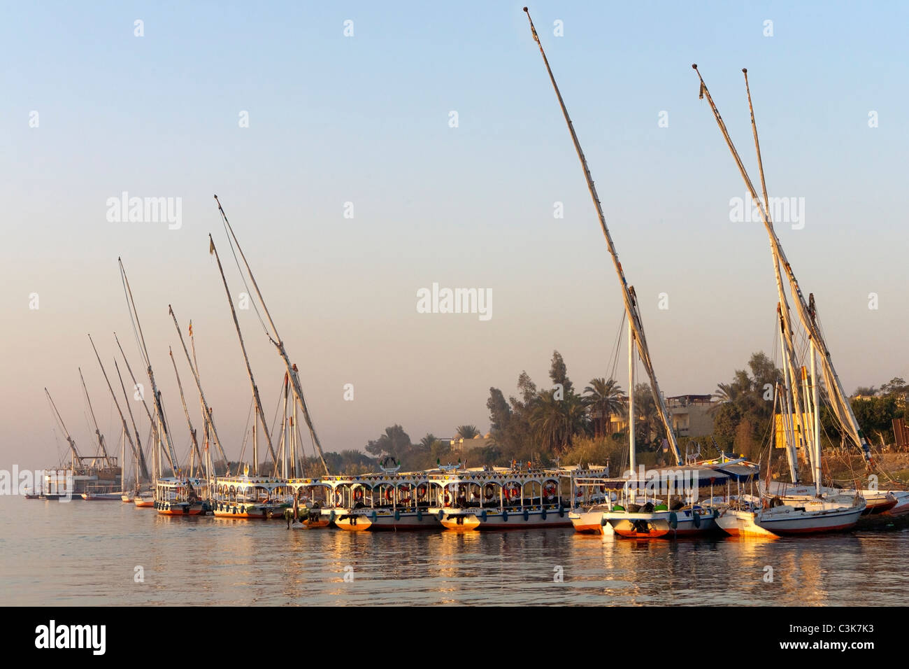 Lance l'eau, les taxis et la felouque sur la rive ouest du Nil au coucher du soleil à Louxor Egypte Banque D'Images
