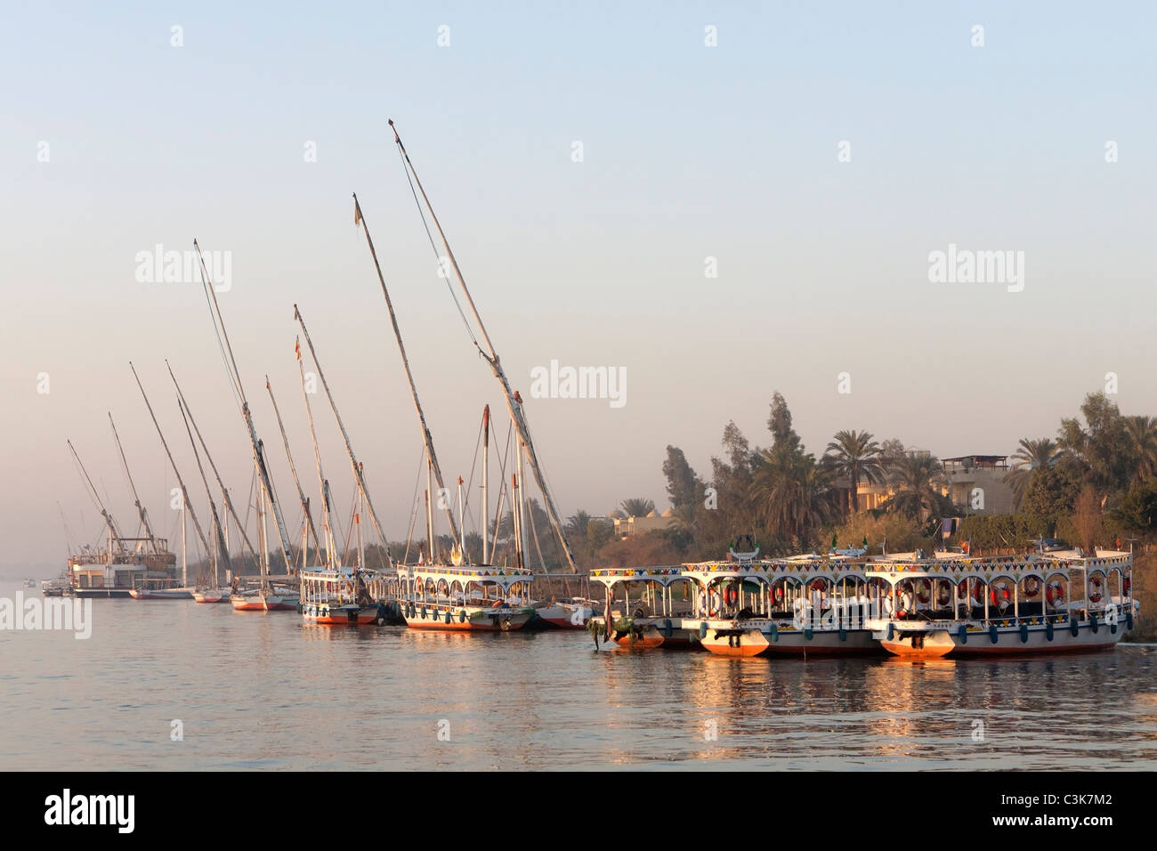 Lance l'eau, les taxis et la felouque sur la rive ouest du Nil au coucher du soleil à Louxor Egypte Banque D'Images