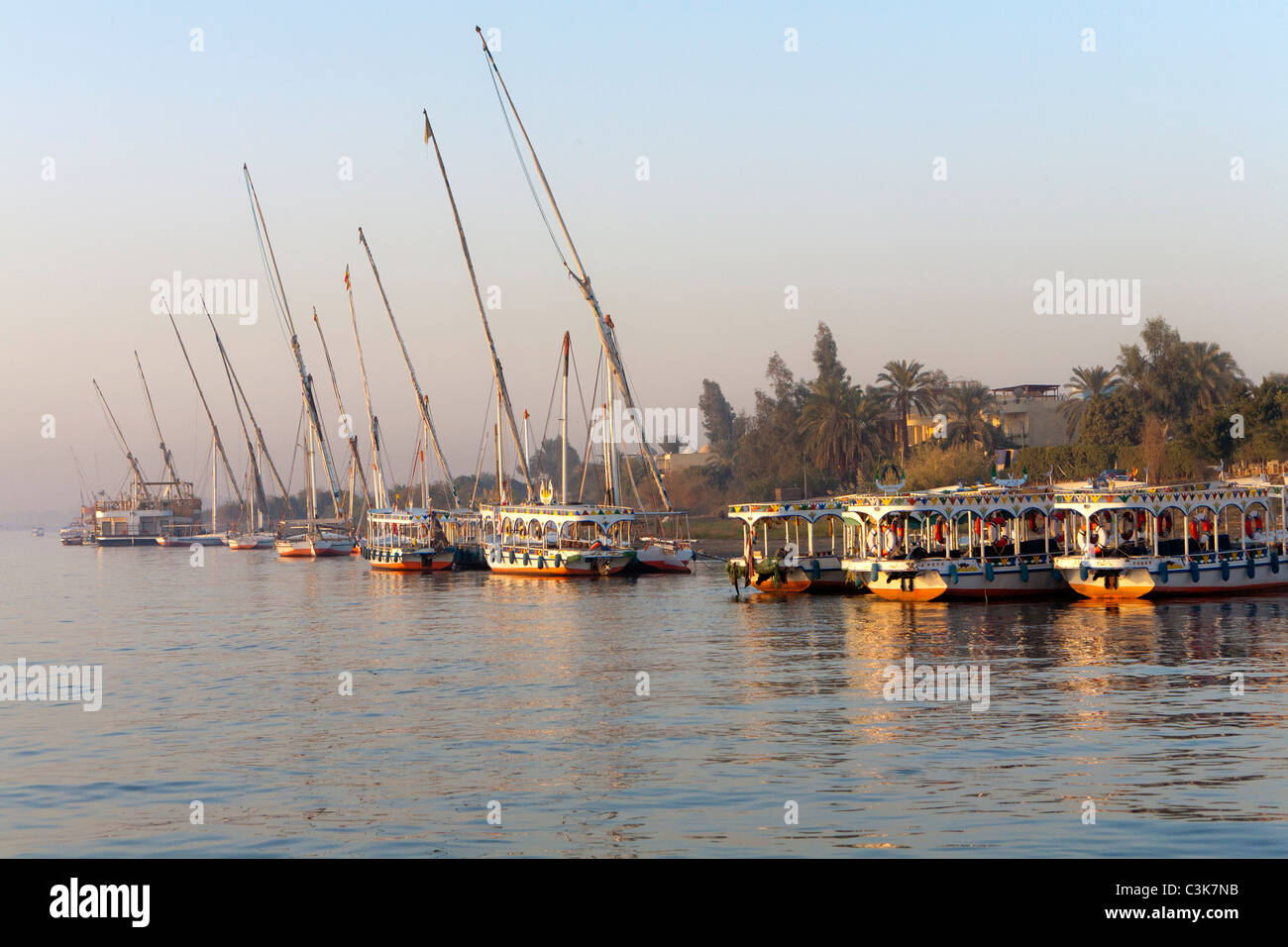 Lance l'eau, les taxis et la felouque sur la rive ouest du Nil au coucher du soleil à Louxor Egypte Banque D'Images