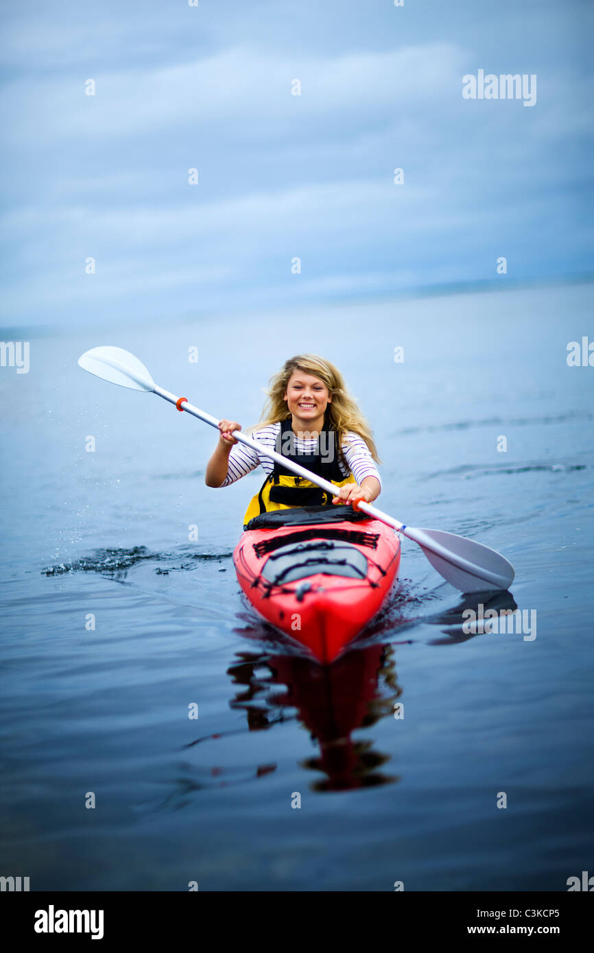 Woman rowing canoe on lake, smiling Banque D'Images