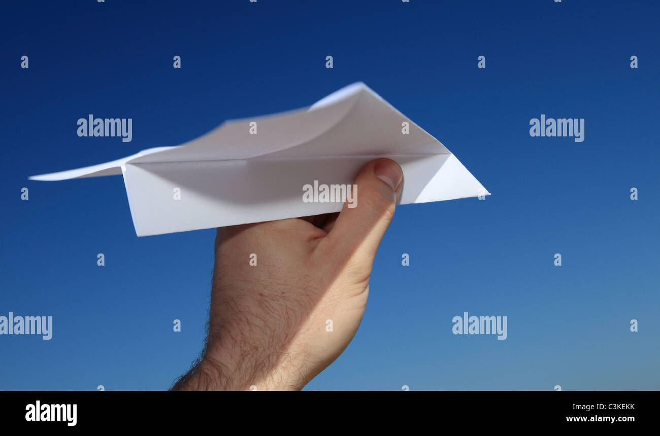 Les personnes d'une main tenant un avion en papier en face de ciel bleu. Banque D'Images Les personnes d'une main tenant un avion en papier en face de ciel bleu. Banque D'Images
