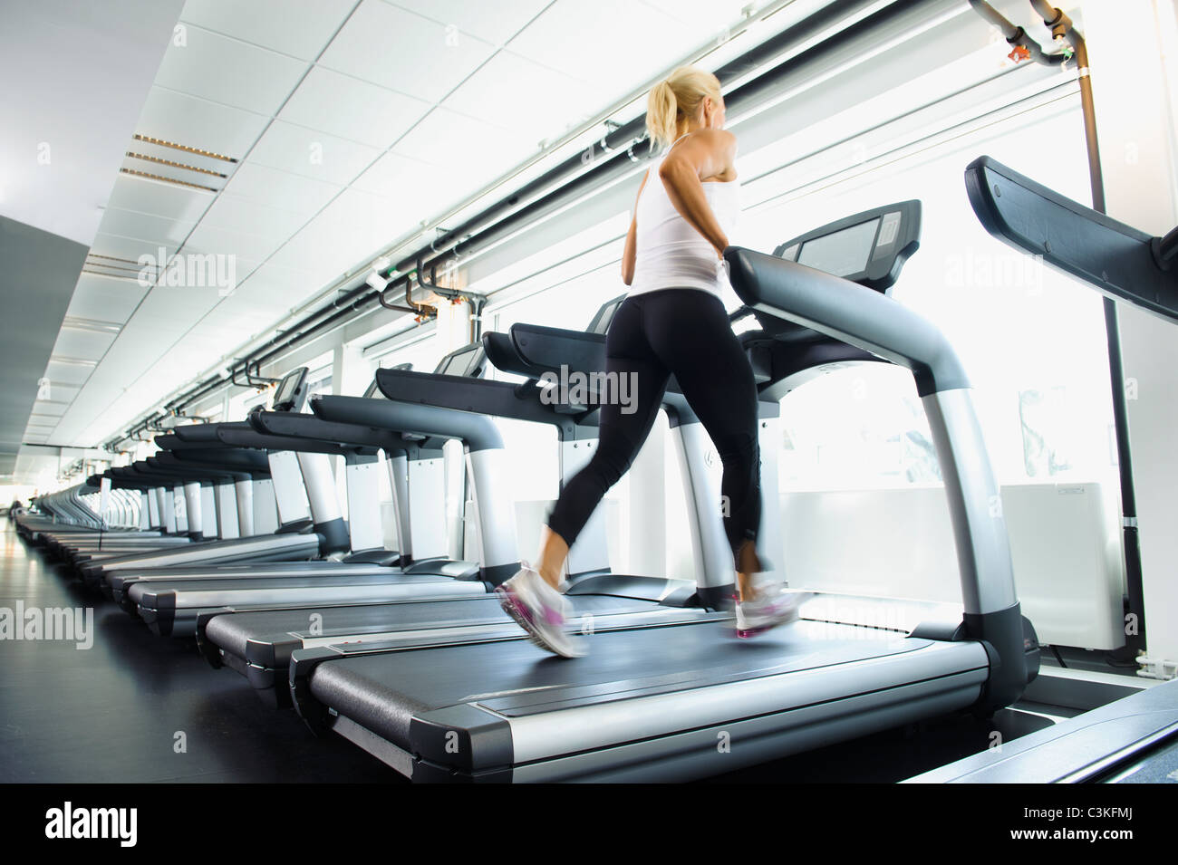 Femme exerçant sur tapis roulant dans une salle de sport Banque D'Images