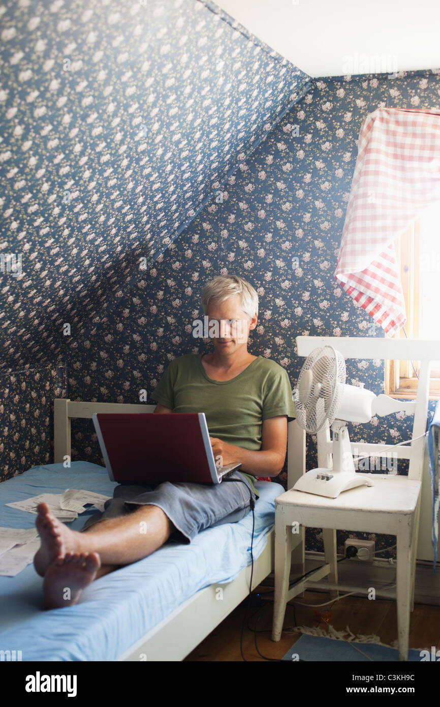 Man using laptop in bed Banque D'Images