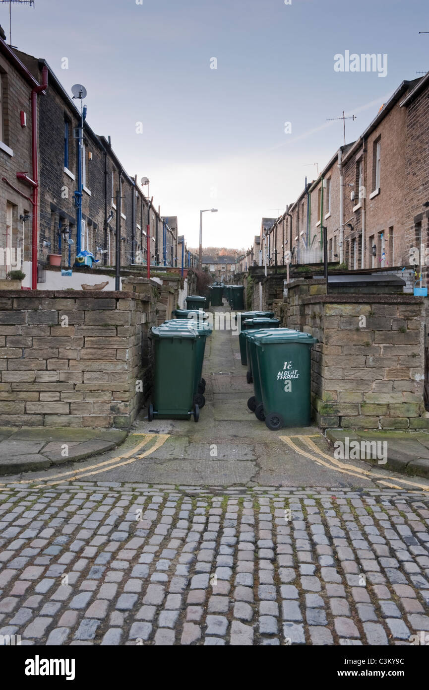 Petite rue à l'arrière d'Albert Terrace, village de Saltaire (2 rangées de maisons mitoyennes, linges à roues vertes alignées, tarets de pierre) - Yorkshire, Angleterre, Royaume-Uni Banque D'Images