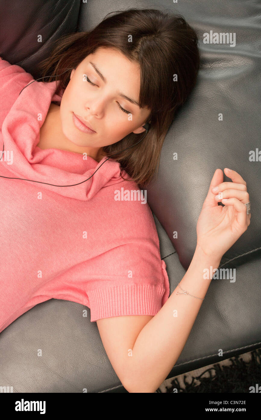 Jeune femme sur un canapé à écouter de la musique Banque D'Images