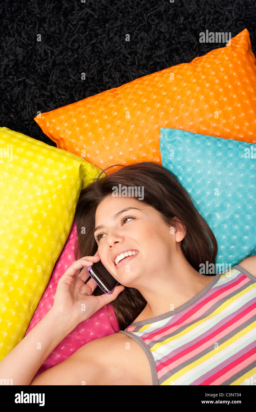 Woman phoning et couché sur des coussins Banque D'Images